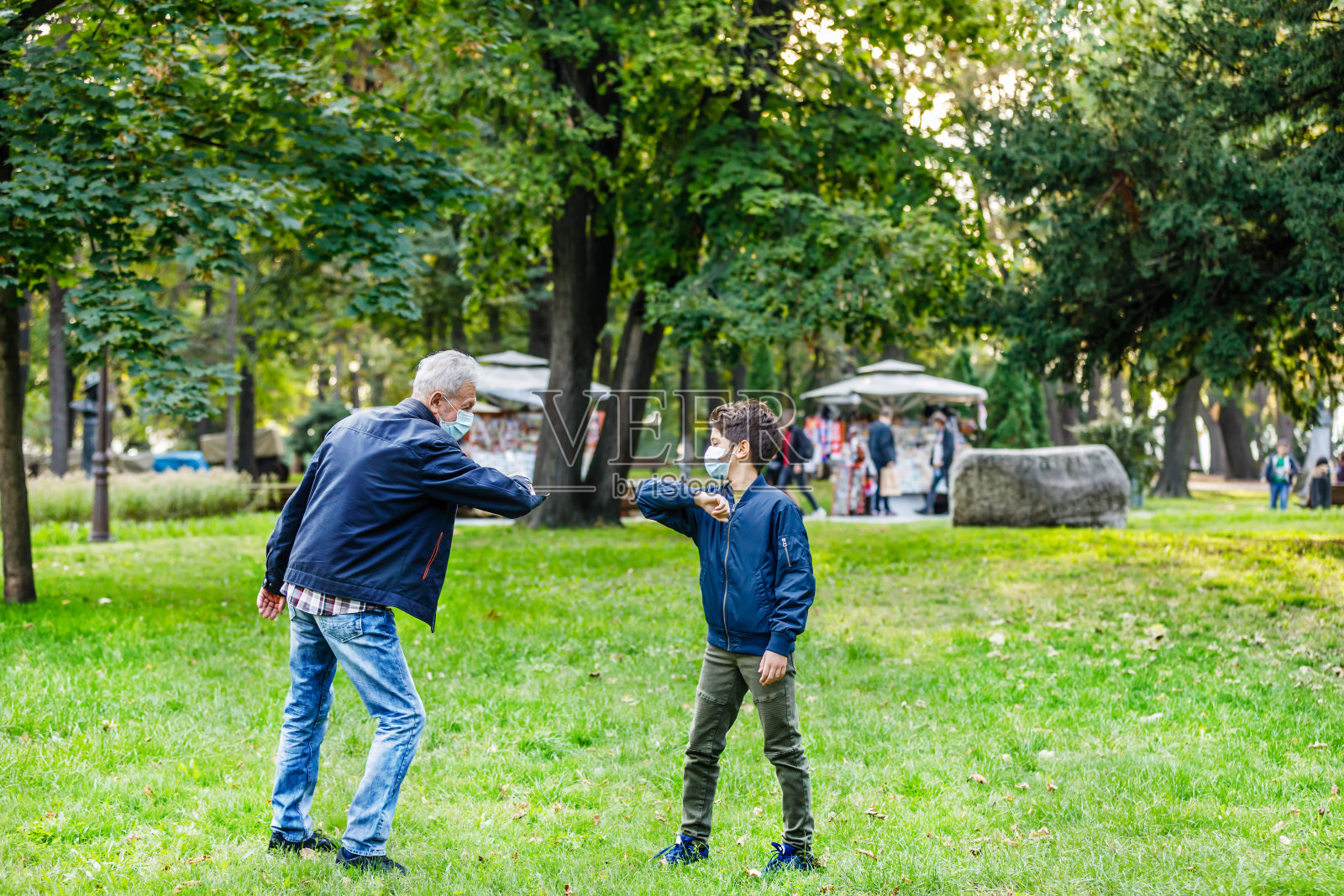 祖父和孙子用肘部打招呼,以避免传播病毒。照片摄影图片
