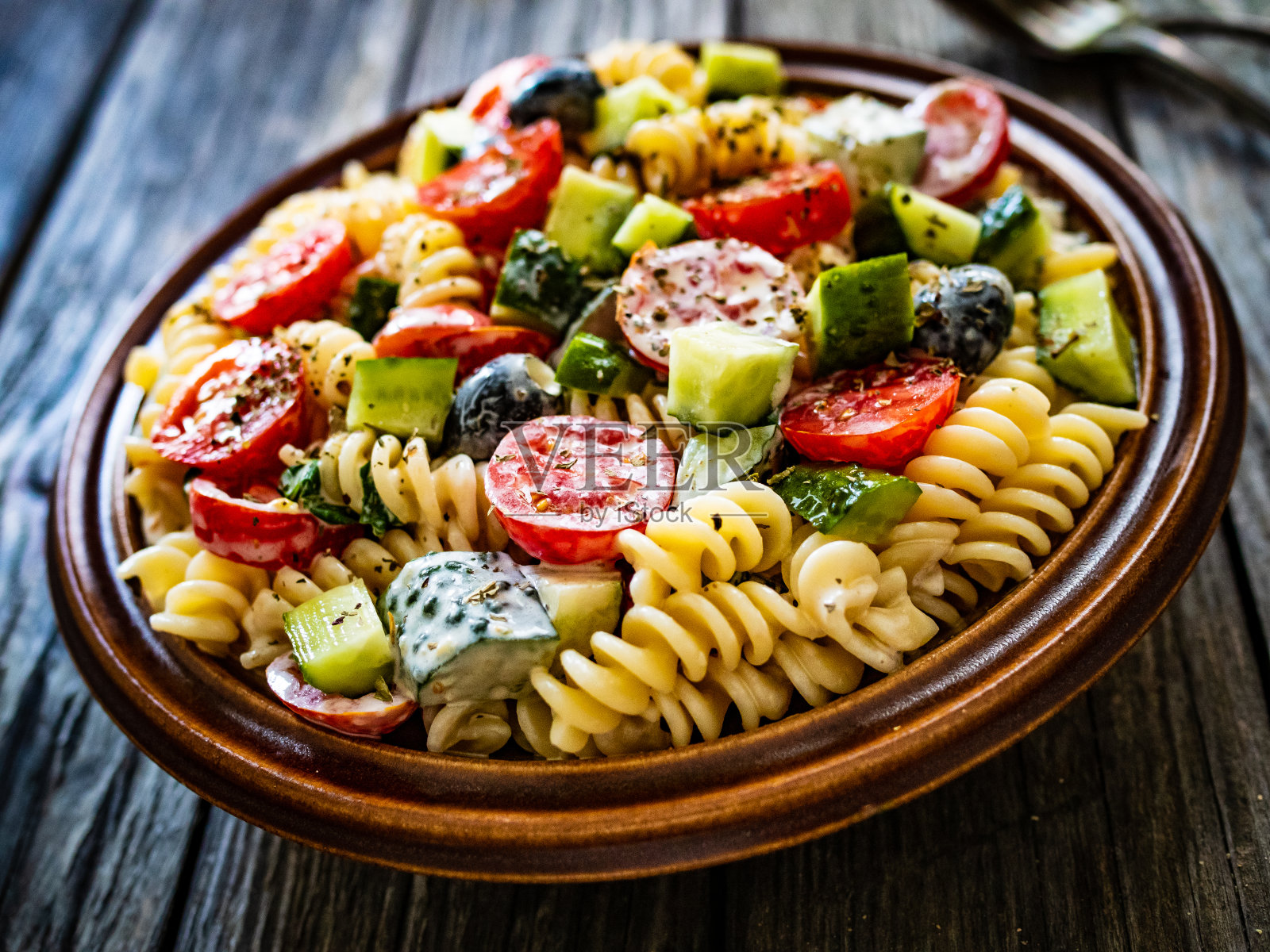 木桌上放有新鲜蔬菜和黑橄榄的意大利面照片摄影图片