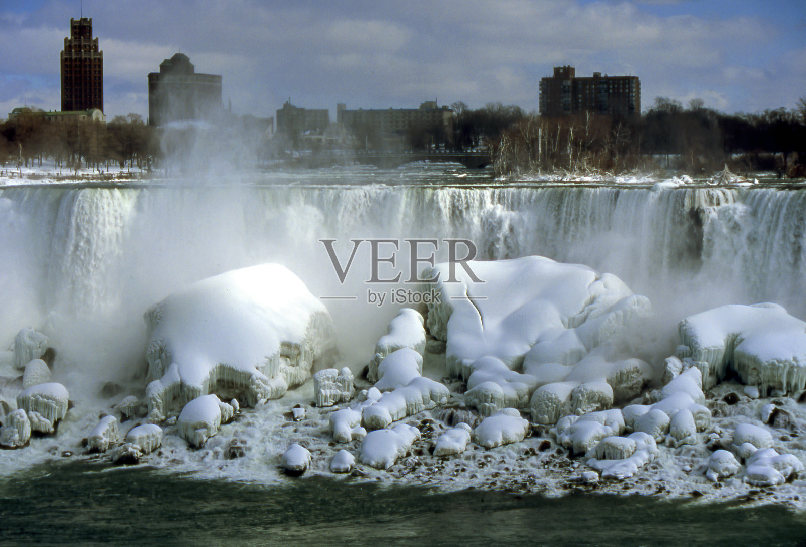 冬天,尼亚加拉瀑布脚下的岩石上覆盖着雪和冰柱照片摄影图片