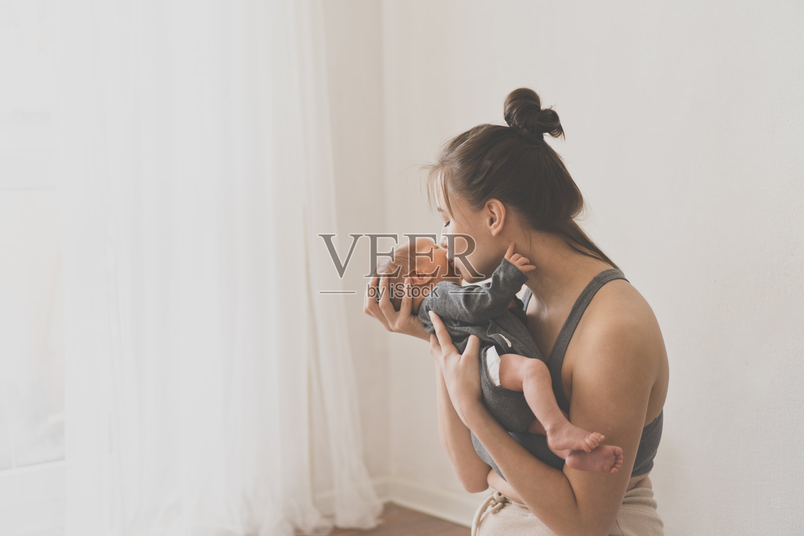 母亲节概念。母亲在家里抱着刚出生的儿子。宝宝和妈妈快乐。照片摄影图片