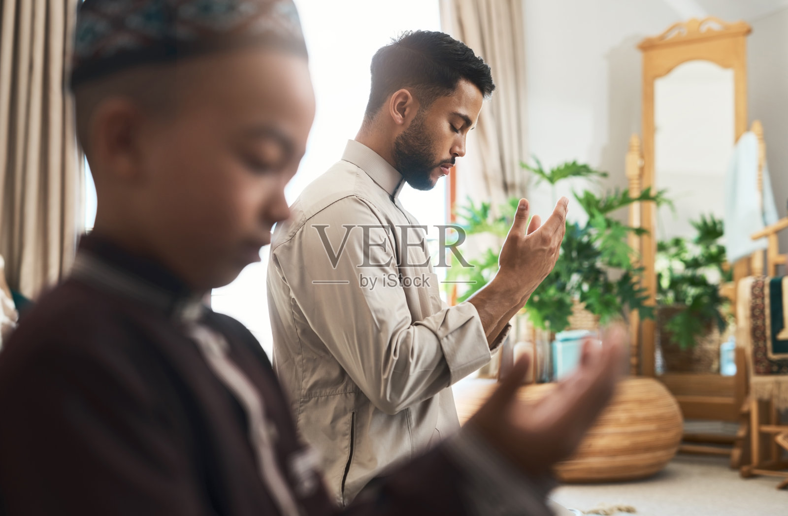 年轻穆斯林男子与儿子在家中休息室祈祷照片摄影图片