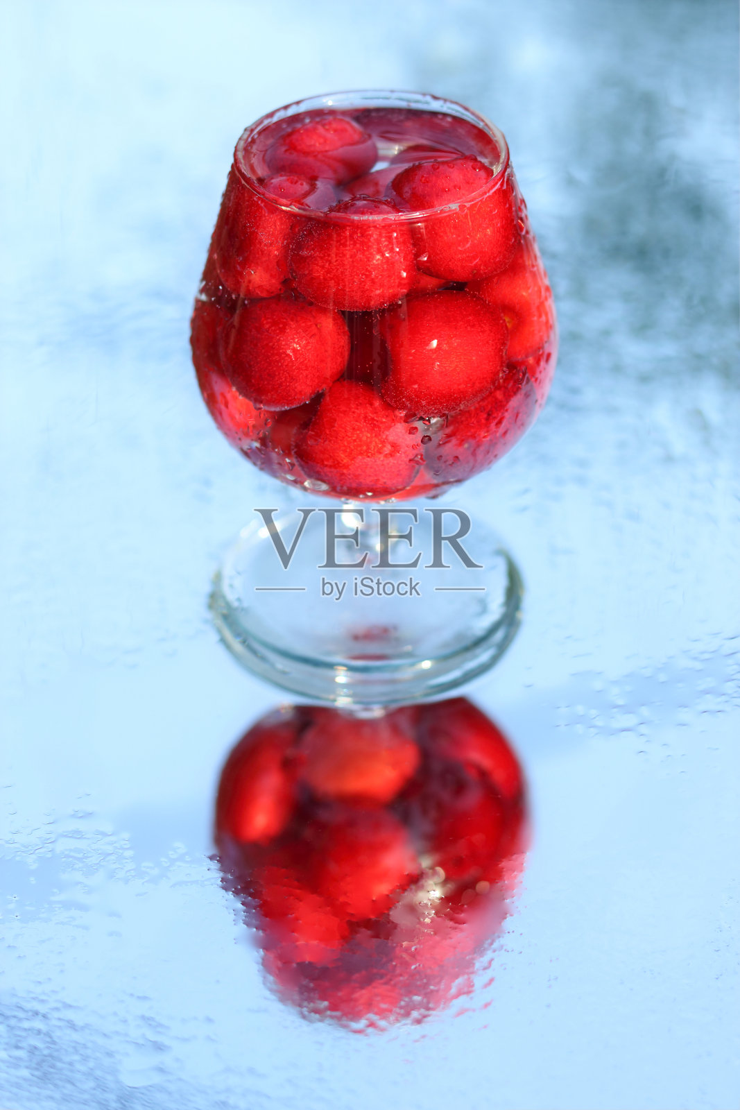 杯子里的樱桃。浆果酒精饮料概念。红酒。樱桃微距细节特写。春天的浆果。季节性的浆果。模糊背景上的樱桃酒或烈酒。自制的红樱桃酊照片摄影图片