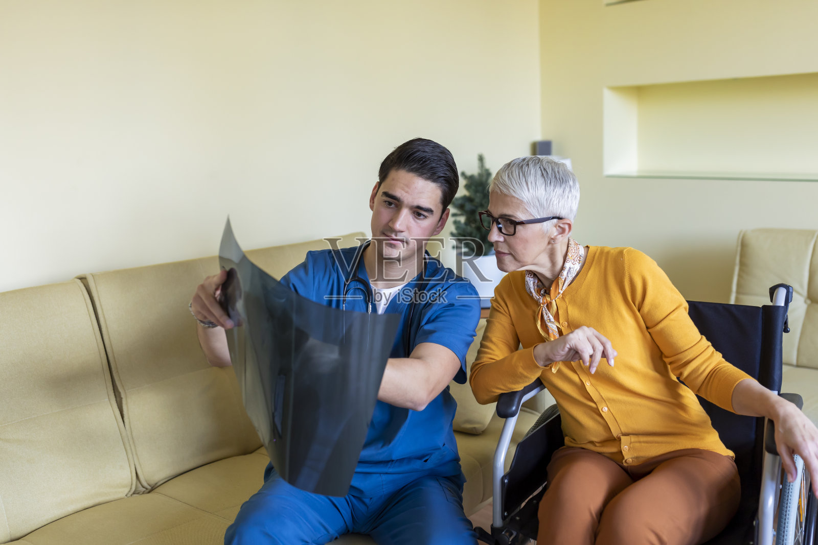 残疾老年妇女和年轻医生花时间一起在家和分析x射线图像。照片摄影图片