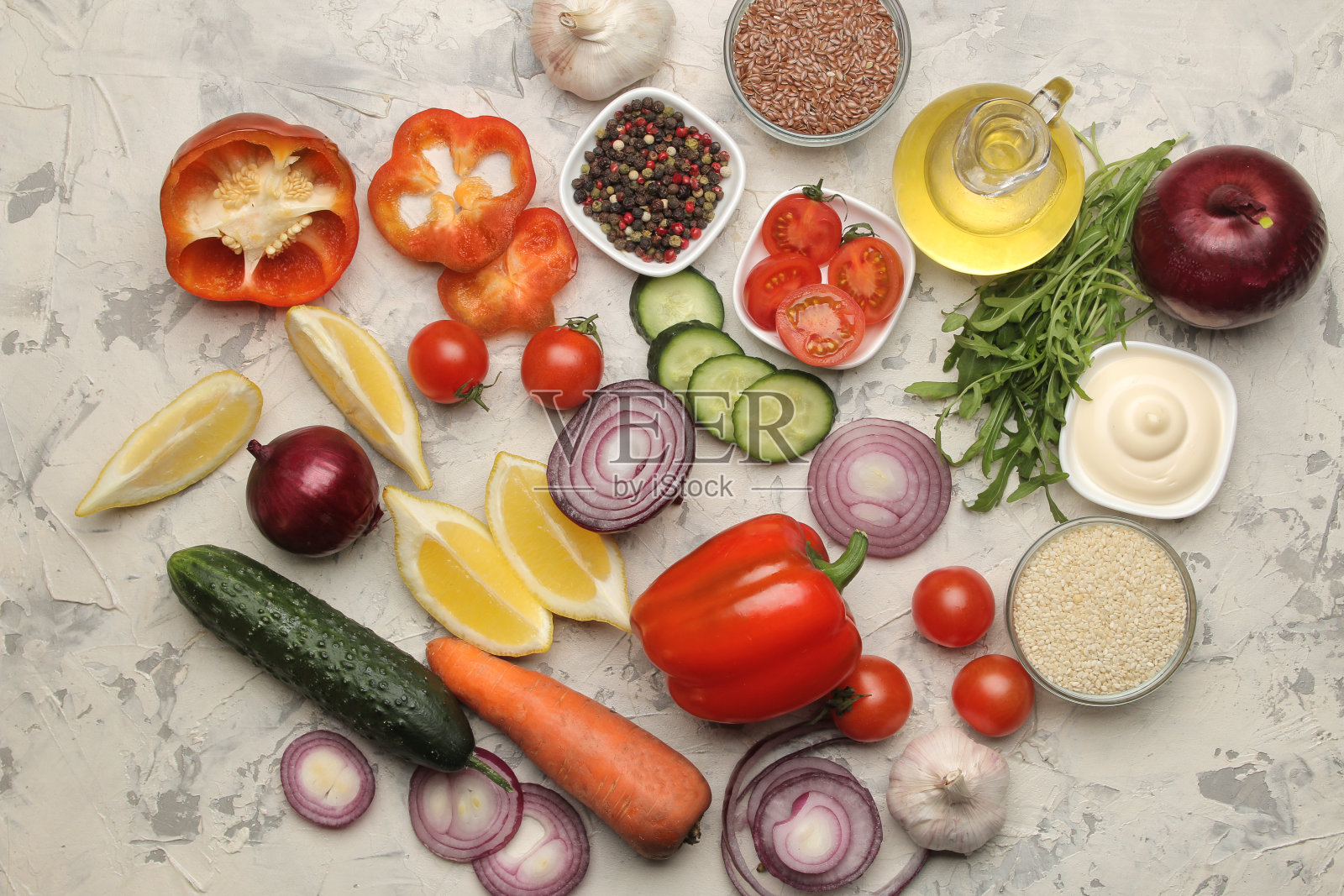 做沙拉的原料。各种蔬菜和香料胡萝卜,西红柿,洋葱,黄瓜,辣椒和芝麻菜在一个明亮的背景。前视图。照片摄影图片