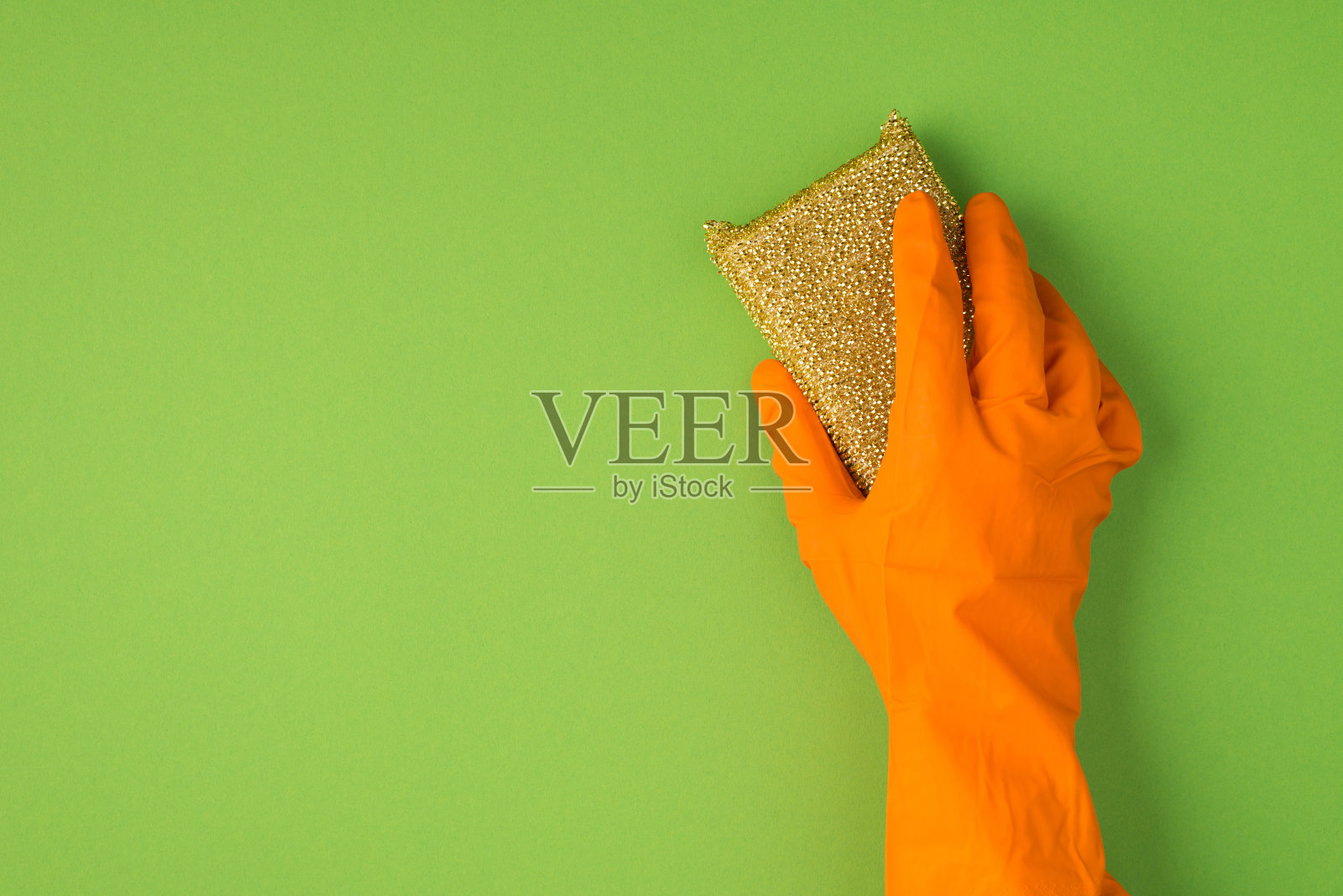 上面的照片是纤维素海绵和橙色手套孤立在绿色背景上照片摄影图片