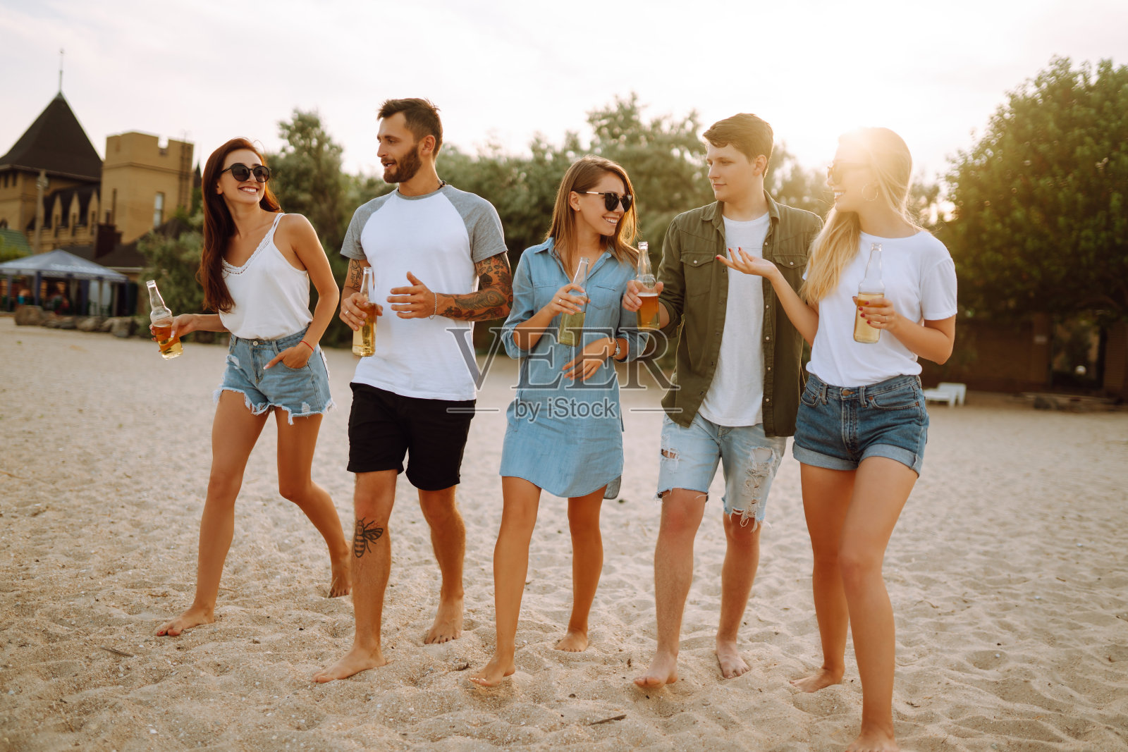 一群朋友在海滩上举杯畅饮。照片摄影图片