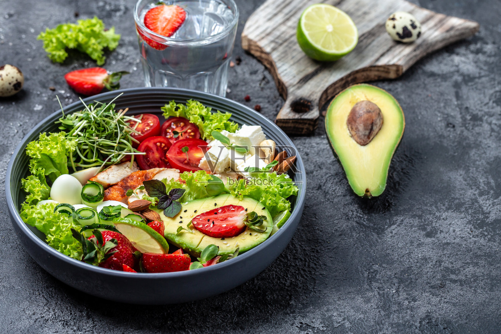 健康的晚餐。佛碗午餐,有烤鸡、牛油果、羊乳酪、鹌鹑蛋、草莓、坚果和莴苣。健康食品的趋势。俯视图照片摄影图片