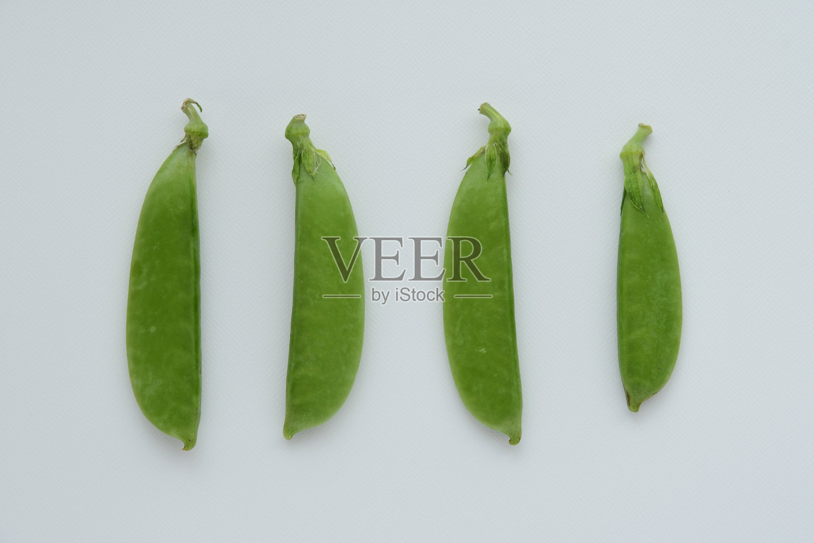 白色背景上的新鲜豌豆。照片摄影图片