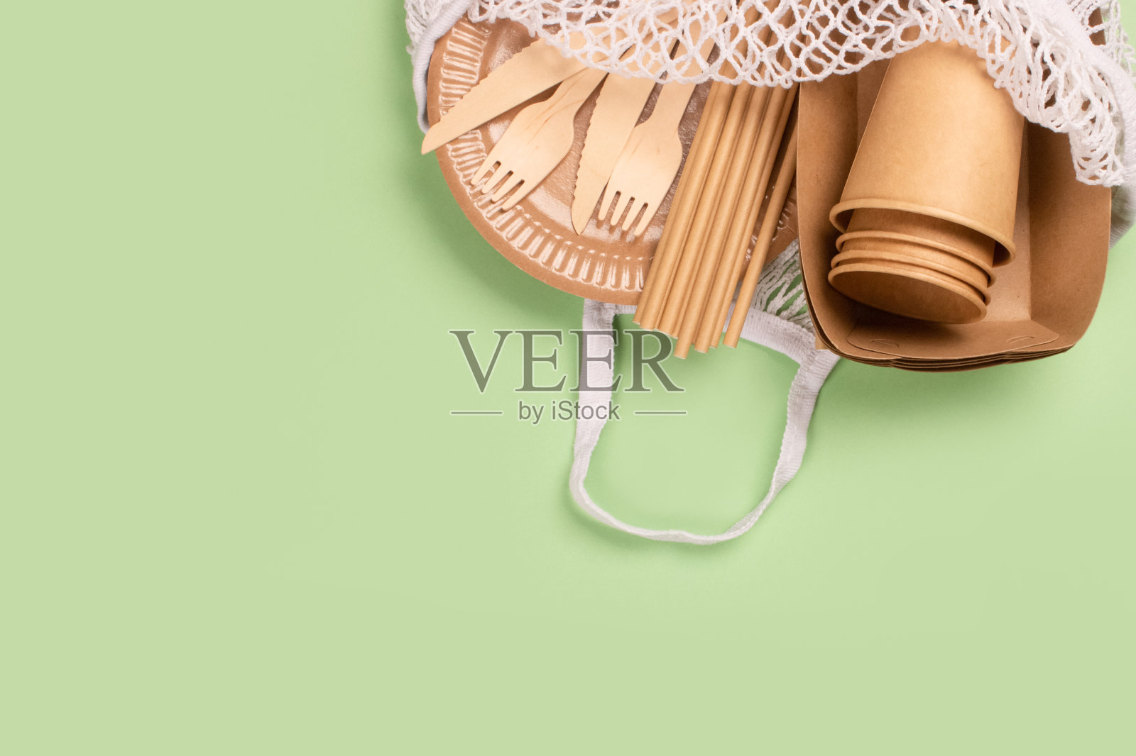 牛皮纸食品杯,盘子和容器与木制餐具在棉花袋绿色背景与复印空间。街头食品纸包装,可持续包装理念。环保餐具照片摄影图片