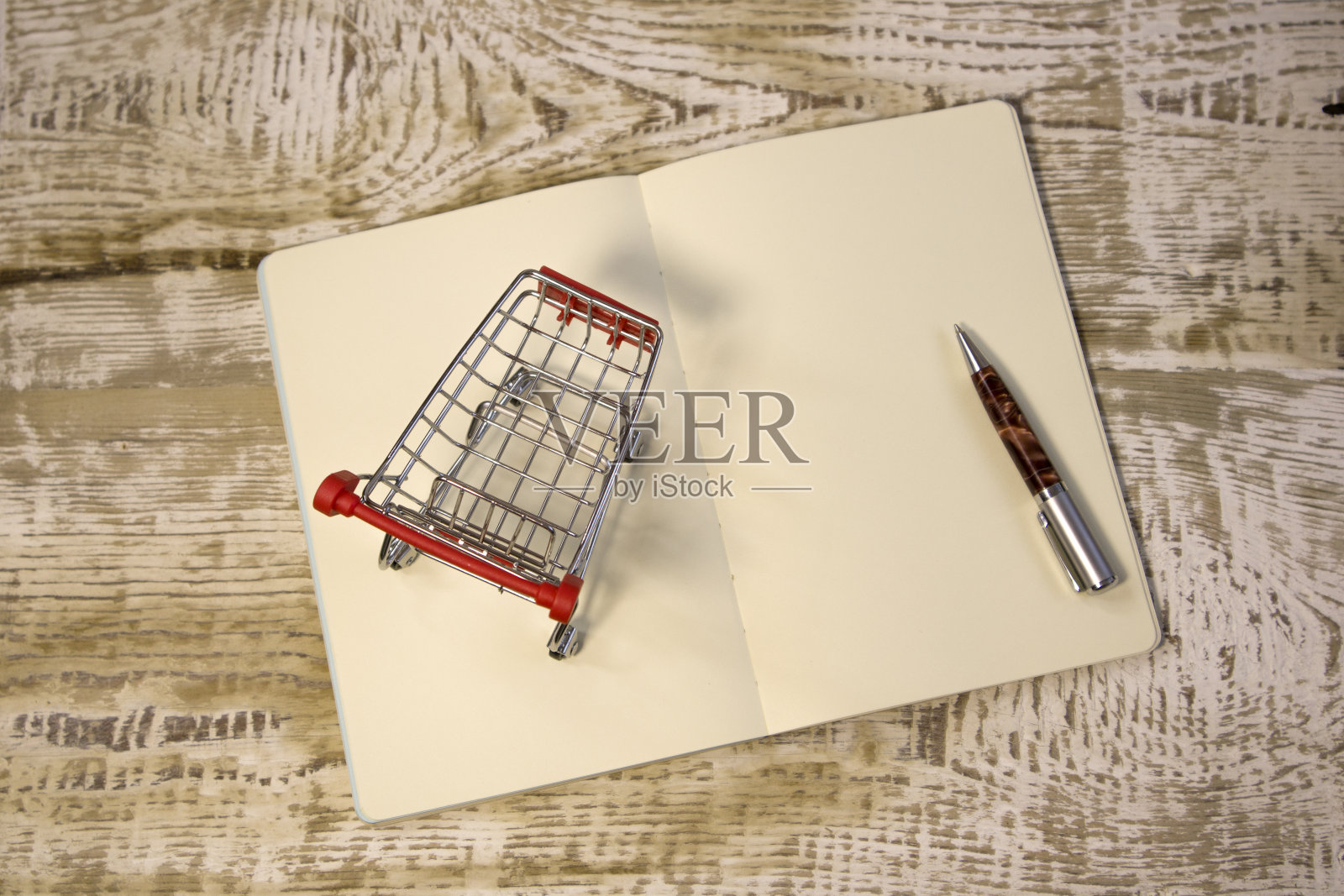 白色空白记事本和小购物车购物车在明亮的红色背景接近购物清单的概念照片摄影图片