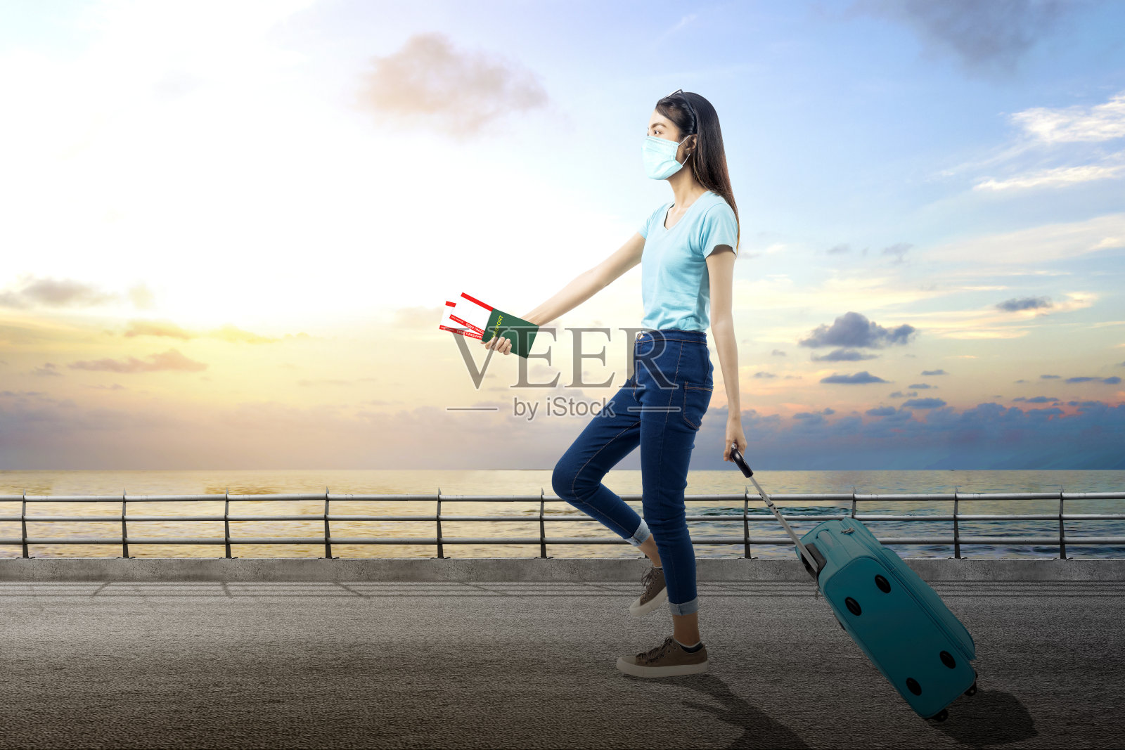 亚洲女人戴着口罩,拿着机票和护照走在行李箱里照片摄影图片