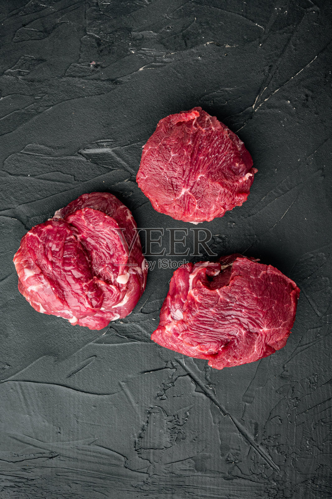 眼睛里脊牛肉大理石的新鲜肉牛排,在黑色的石头背景,顶部视图平lay,与文本的复制空间照片摄影图片