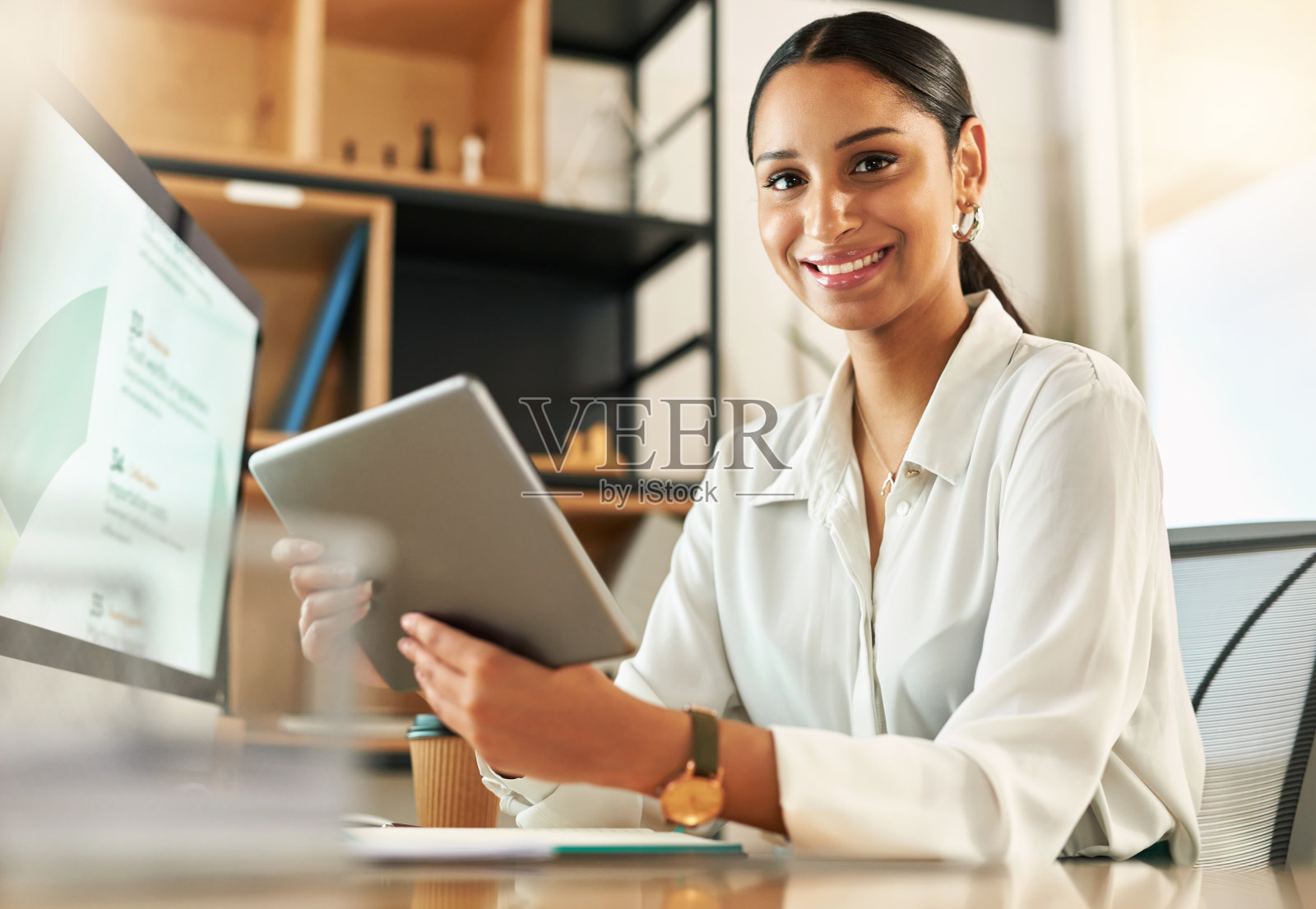 一位年轻的女商人在她的办公桌上使用她的电子平板电脑照片摄影图片