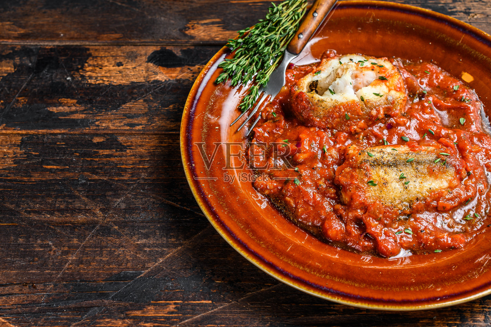 烤白鱼片配蕃茄酱在盘子里。黑暗的背景。前视图。本空间照片摄影图片