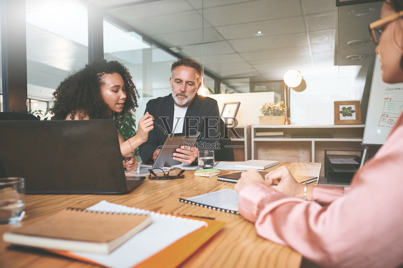 两名商务人士坐在办公室里,一边使用电子平板电脑一边讨论照片摄影图片