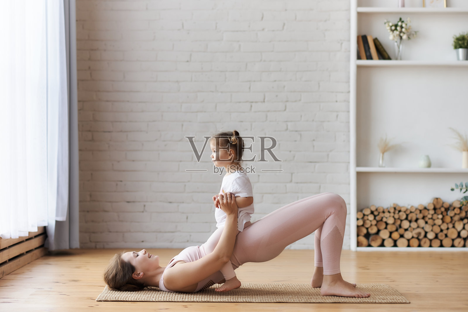 年轻微笑的女人在浅粉色做臀部锻炼和骨盆倾斜骨盆卷曲的姿势照片摄影图片