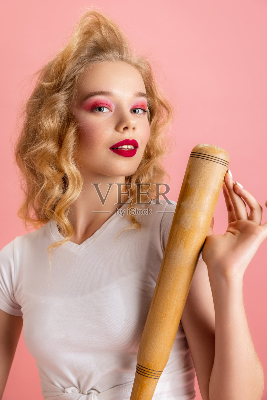 美丽的年轻女孩明亮的妆和发型在复古90年代时尚风格的形象哈利奎恩孤立在粉红色的工作室背景。时代比较的概念照片摄影图片