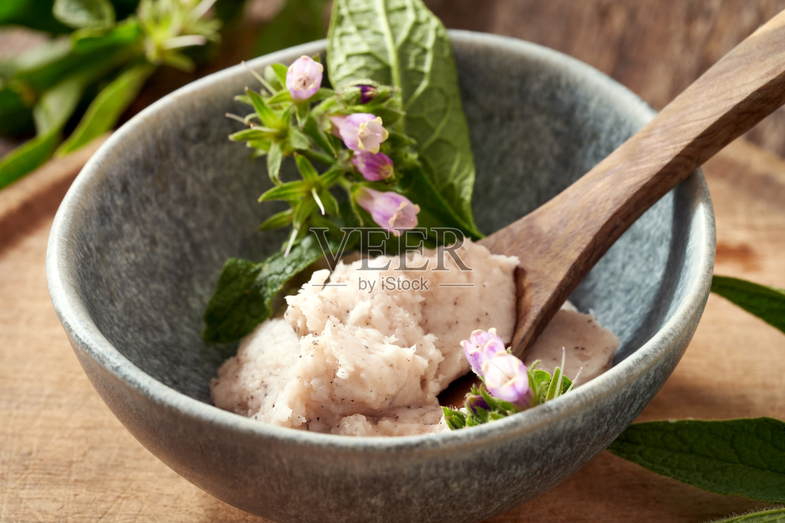 一碗自制的紫草根药膏,里面有新鲜盛开的菊花照片摄影图片