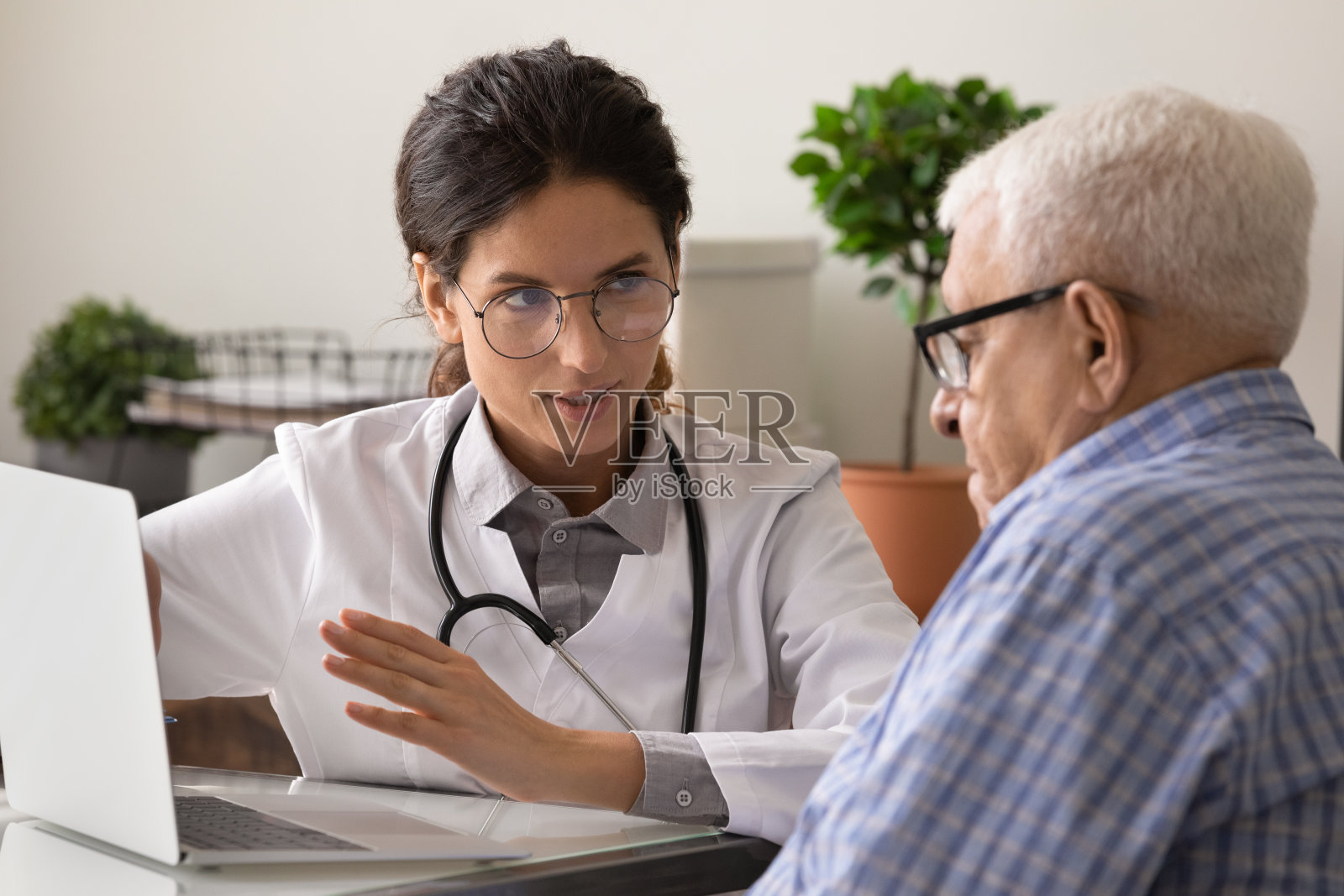 女医生和老年男患者在诊所使用笔记本电脑照片摄影图片