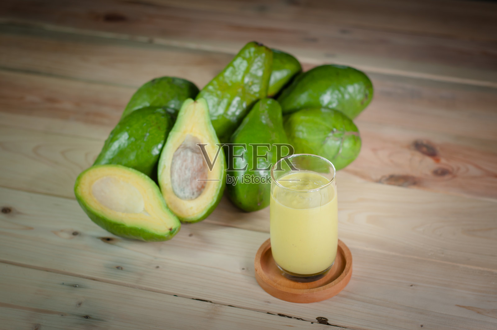 新鲜牛油果和牛油果汁装在玻璃木桌上照片摄影图片