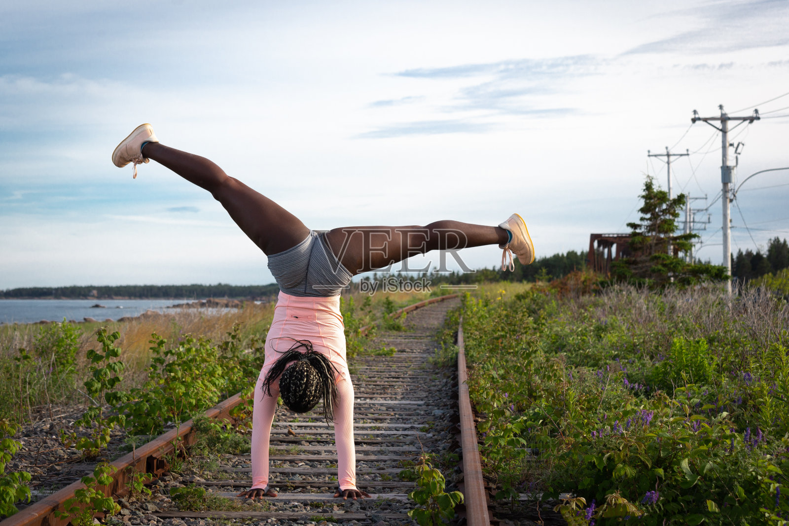 体操运动员在铁轨上练习倒立照片摄影图片
