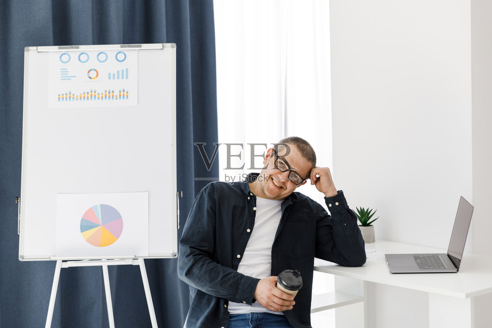 一名穿着便服的男子在办公室里用笔记本电脑工作,表达积极的情绪照片摄影图片