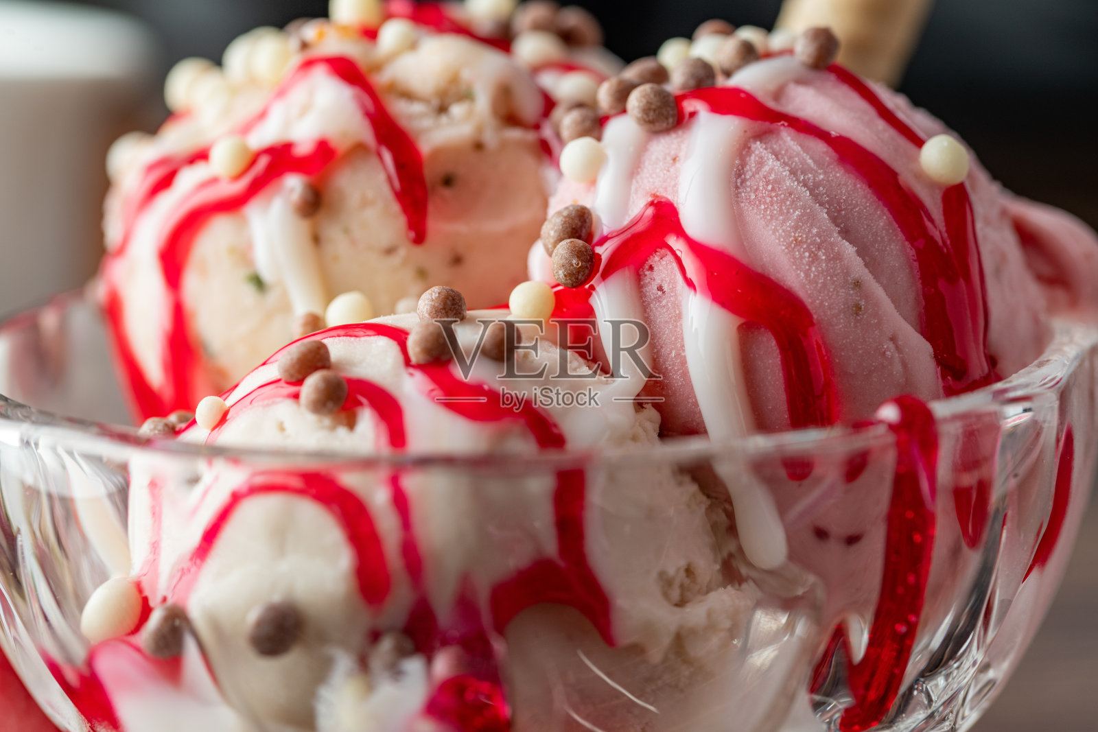 草莓、香蕉和奶油罗马冰淇淋,放在玻璃碗里,上面浇上红酱。照片摄影图片