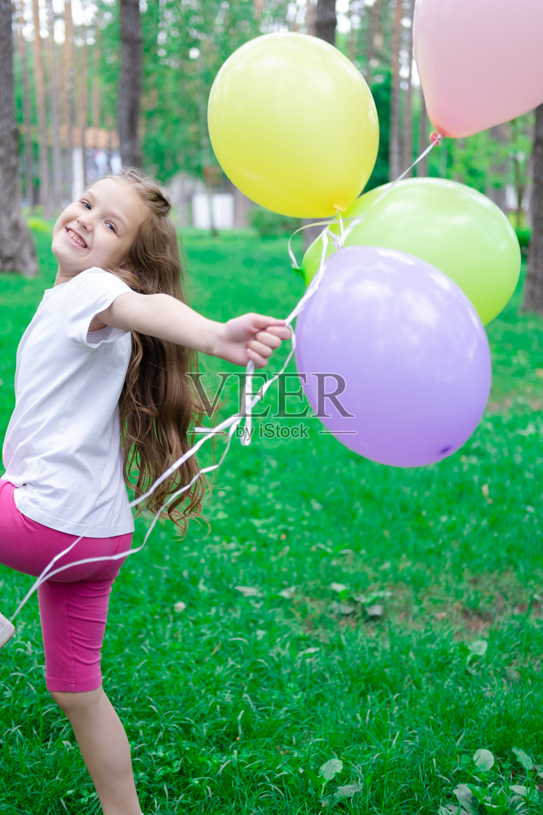 漂亮的学前班女孩在户外玩热气球玩得很开心。节假日,派对,生日,庆祝。快乐的孩子照片摄影图片