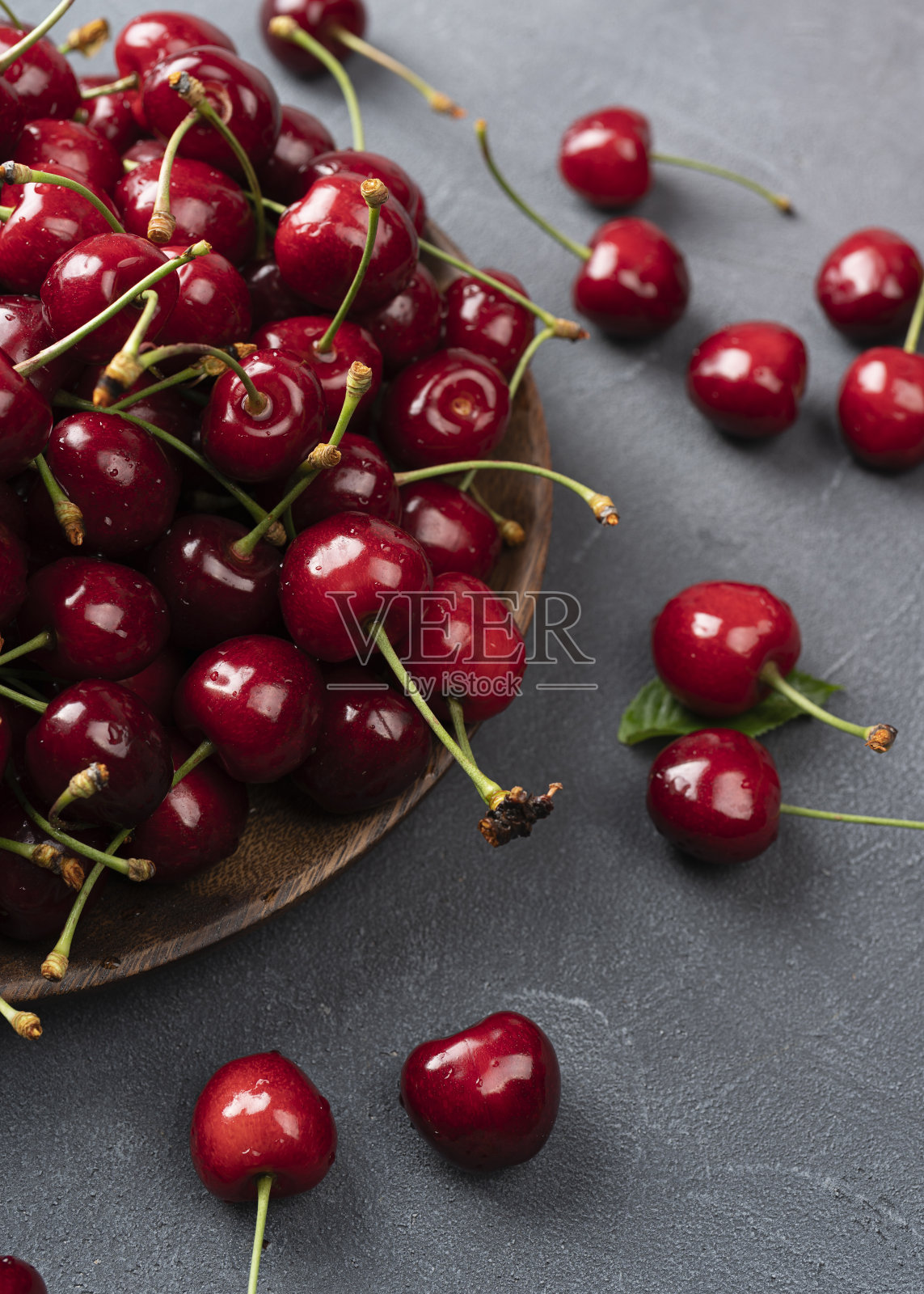 新鲜甜樱桃碗与树叶在石头背景上的水滴照片摄影图片