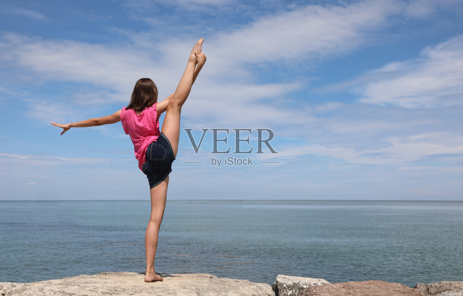 一个白人女孩在夏天表演艺术体操,腿向上,脚过头顶照片摄影图片