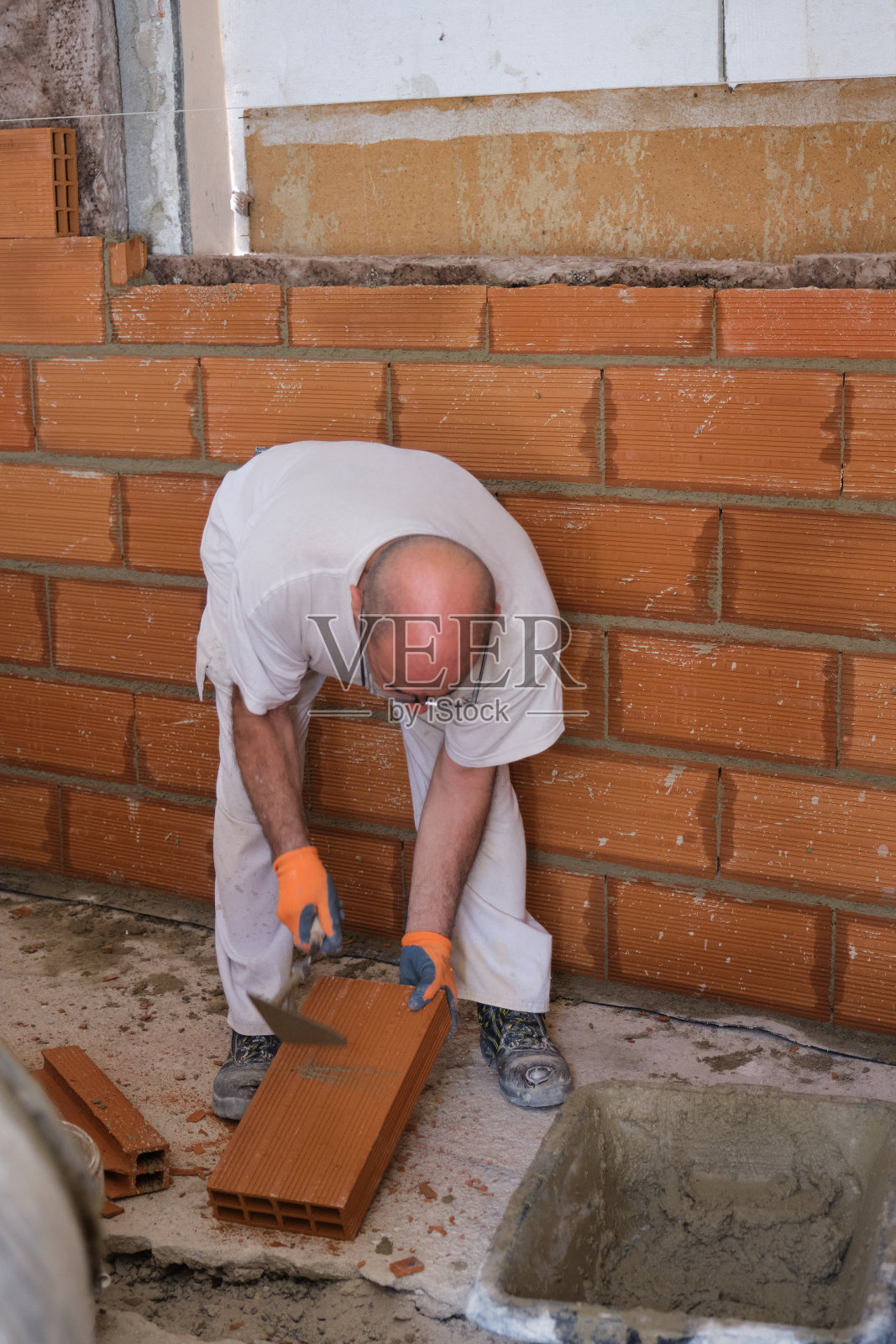 建筑工打碎一块砖,把它固定在墙上。照片摄影图片