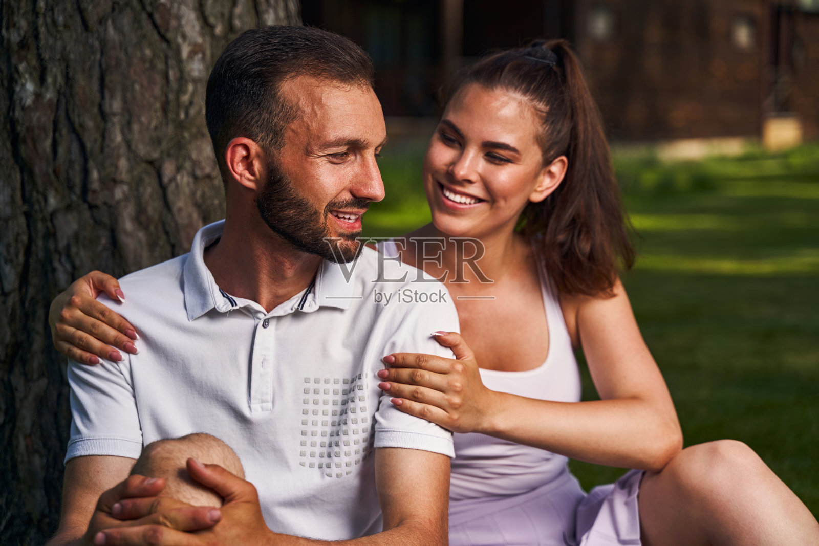 一对相爱的情侣坐在外面的一棵树旁照片摄影图片