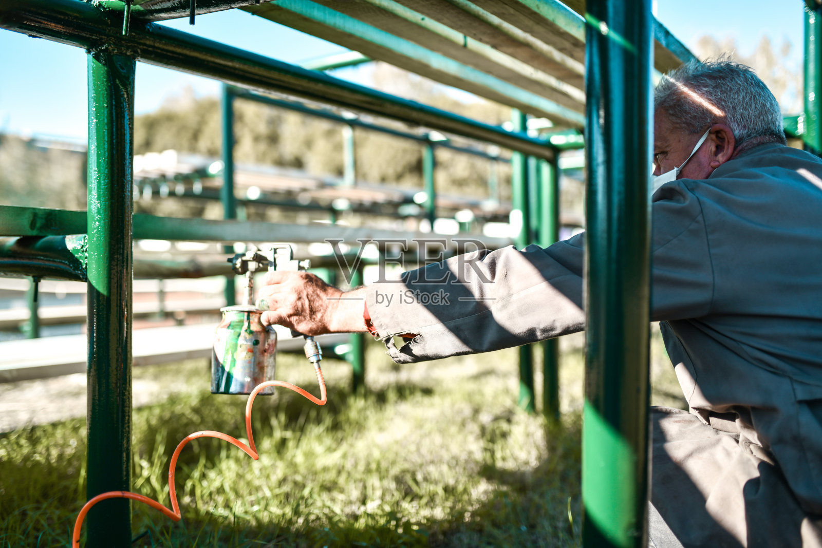 穿着破制服的高级画家在大看台上努力工作照片摄影图片