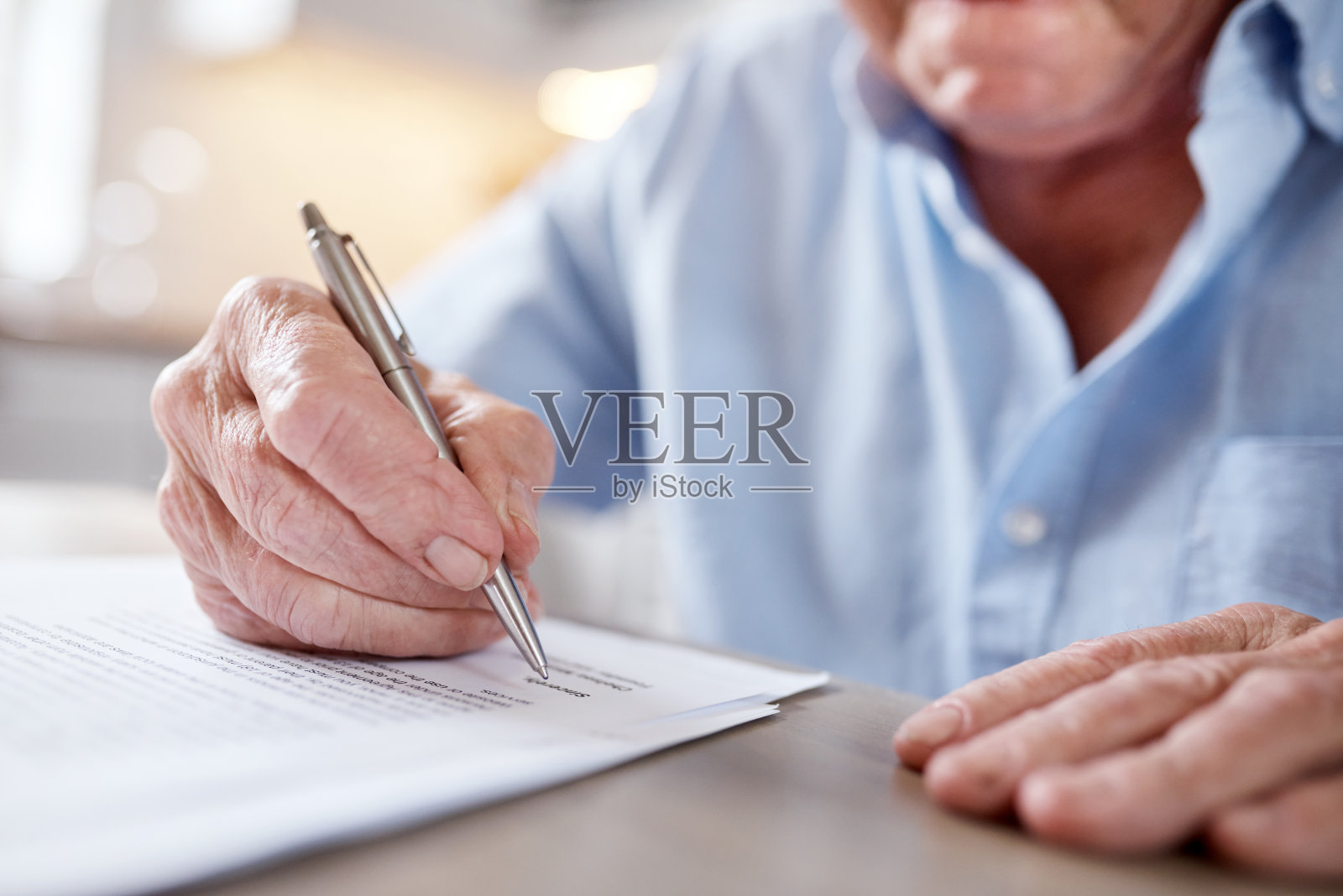 一个不知名的男人在家里的餐桌上填写表格照片摄影图片