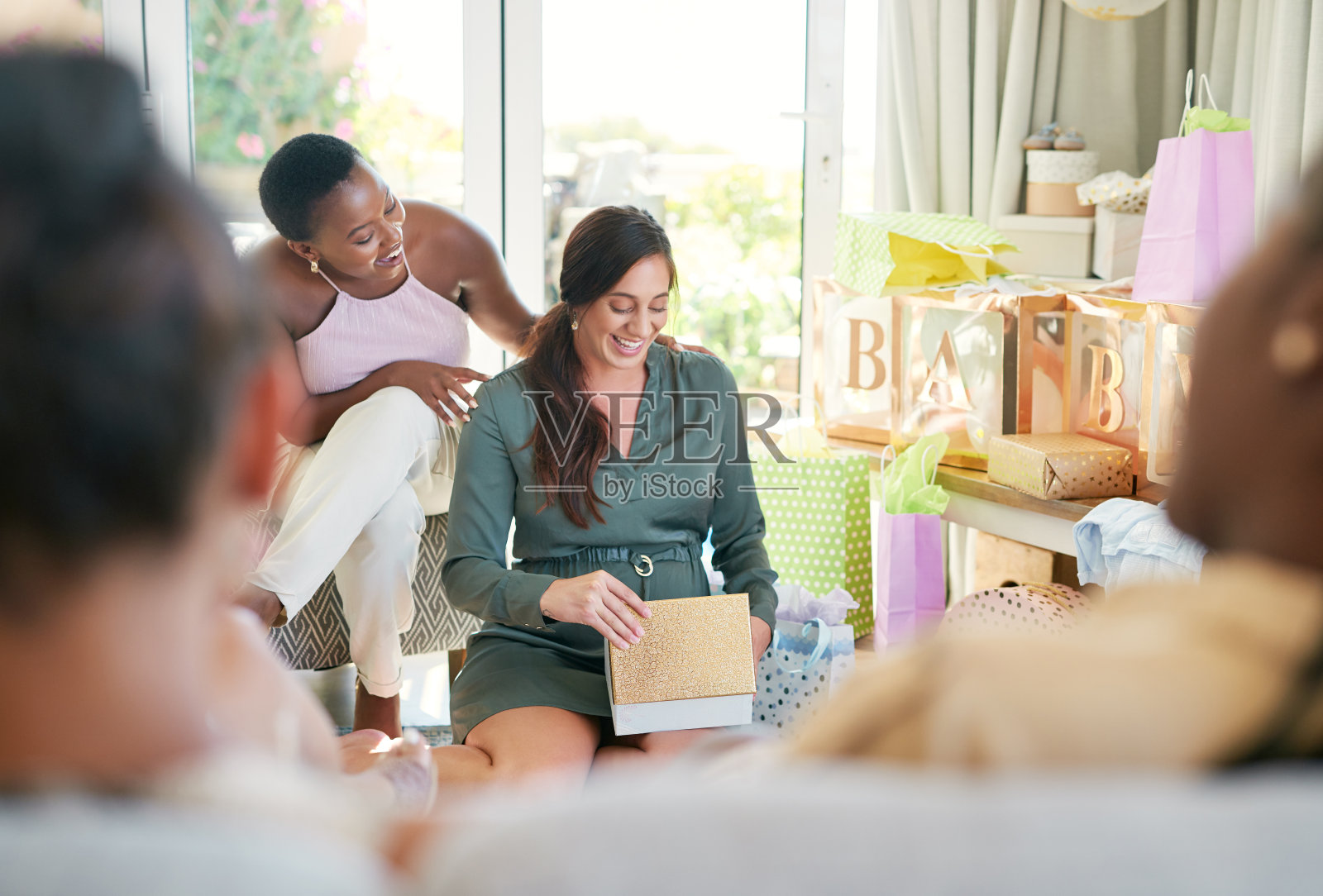 照片中,一位年轻的母亲在婴儿送礼会上打开朋友送给她的礼物照片摄影图片