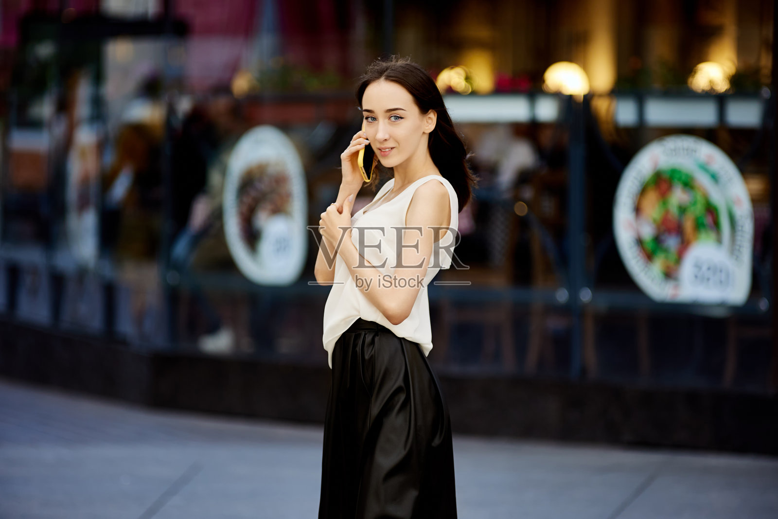 苗条的年轻女子在户外用手机聊天。照片摄影图片