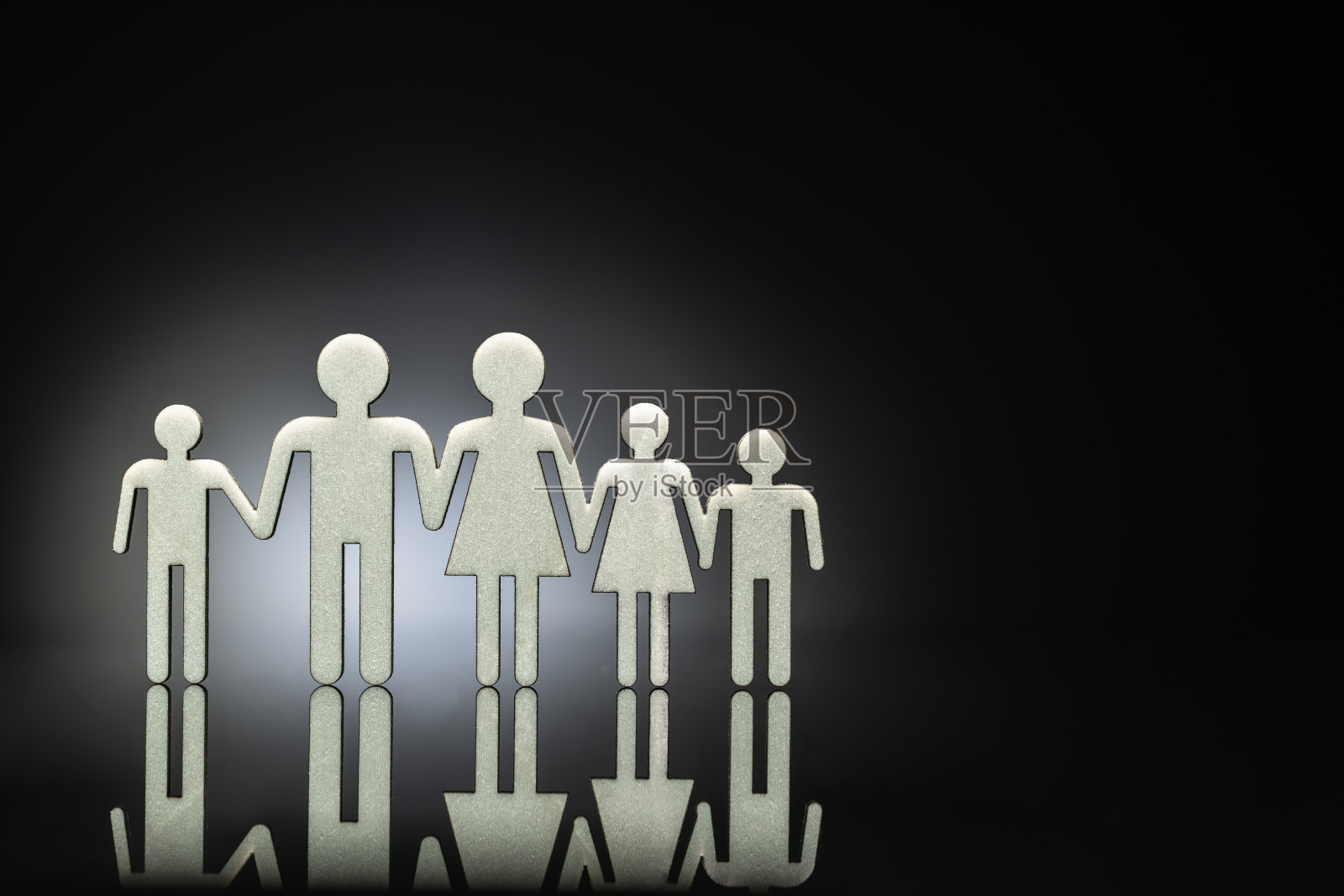 2D家庭符号在胶合板上制作,并放置在黑色背景的反射玻璃上,作为团队工作。照片摄影图片