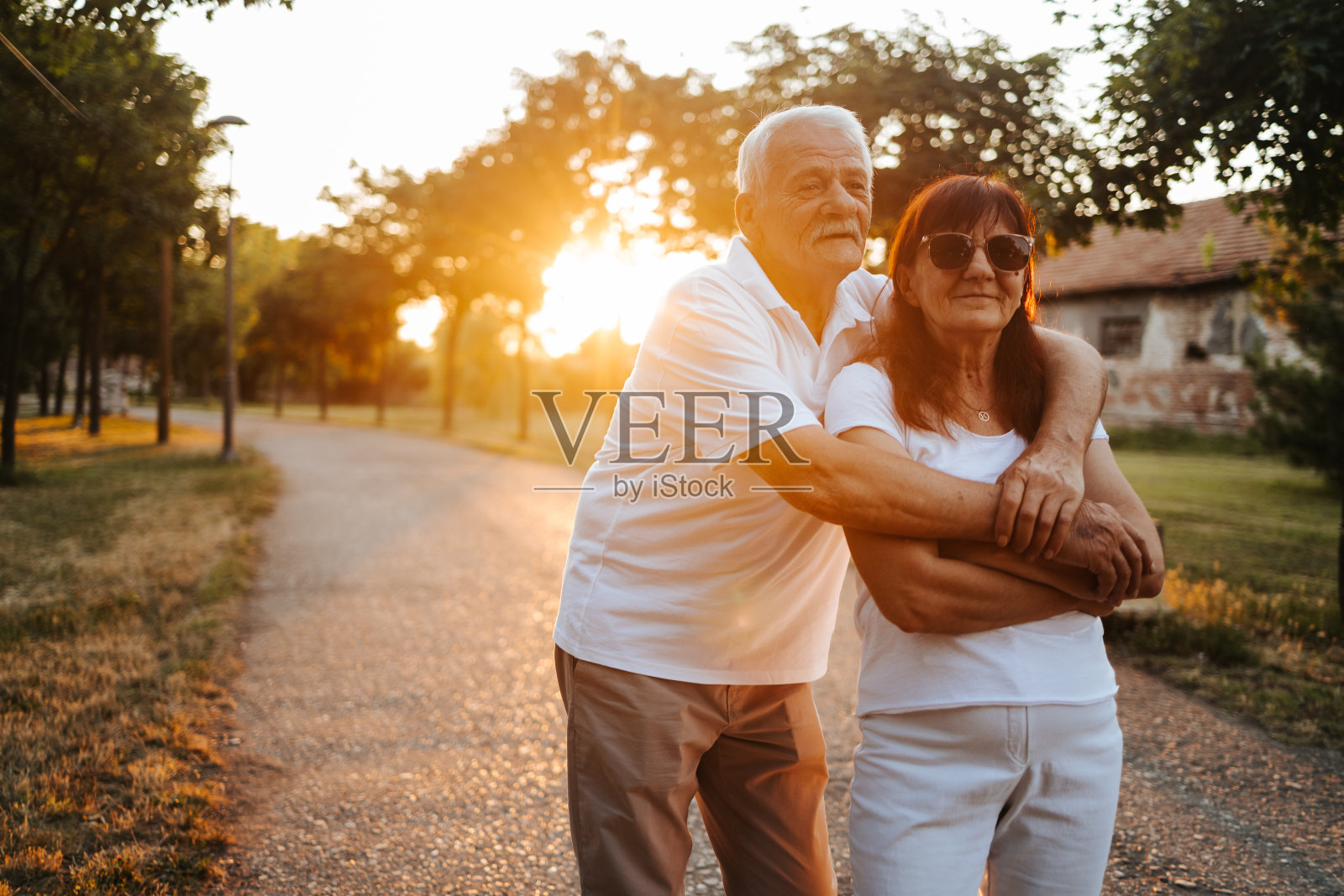 日落时分,一对幸福的老夫妇在公园里享受夏天。照片摄影图片