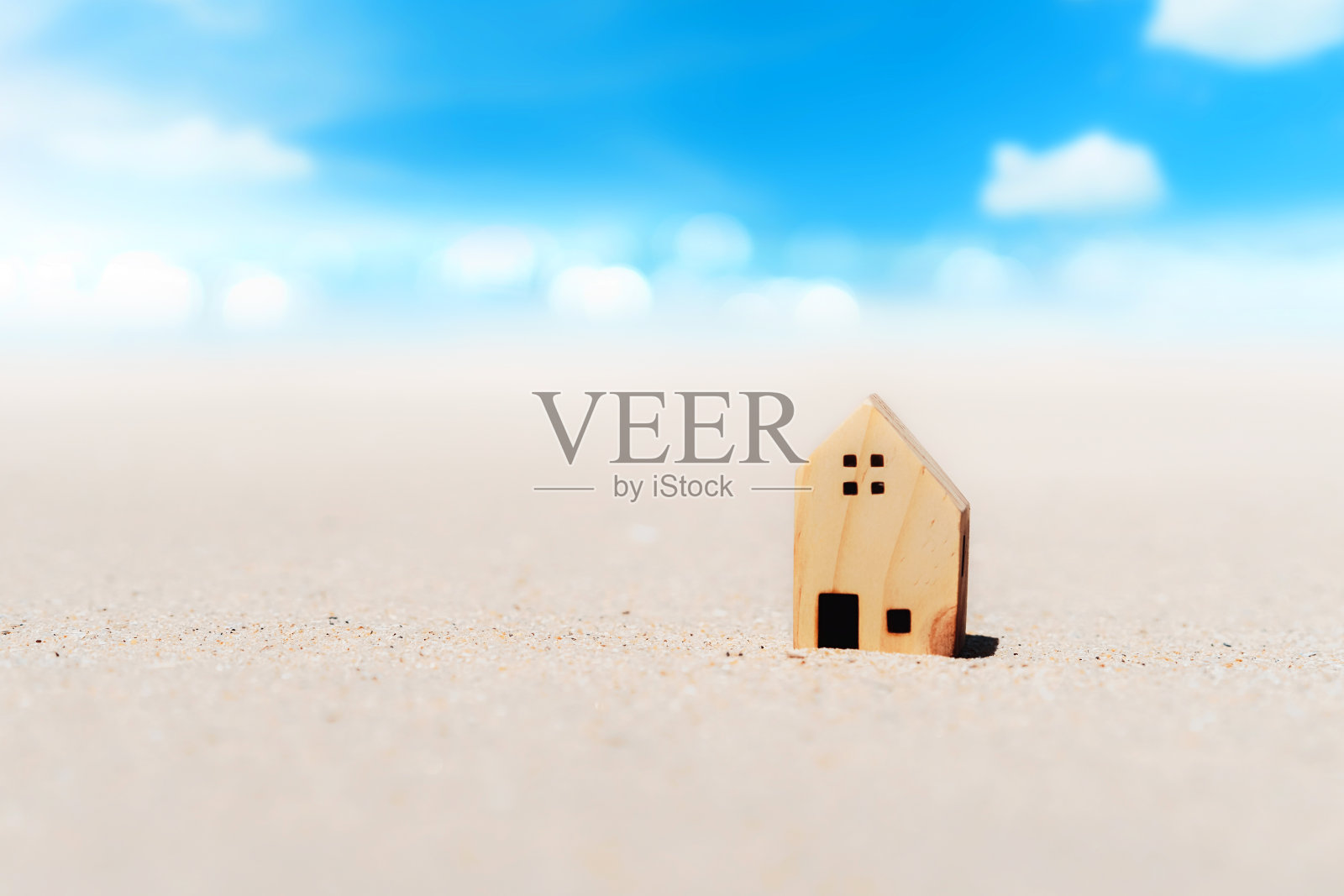 沙滩上的小房子模型,蓝天白云背景。照片摄影图片