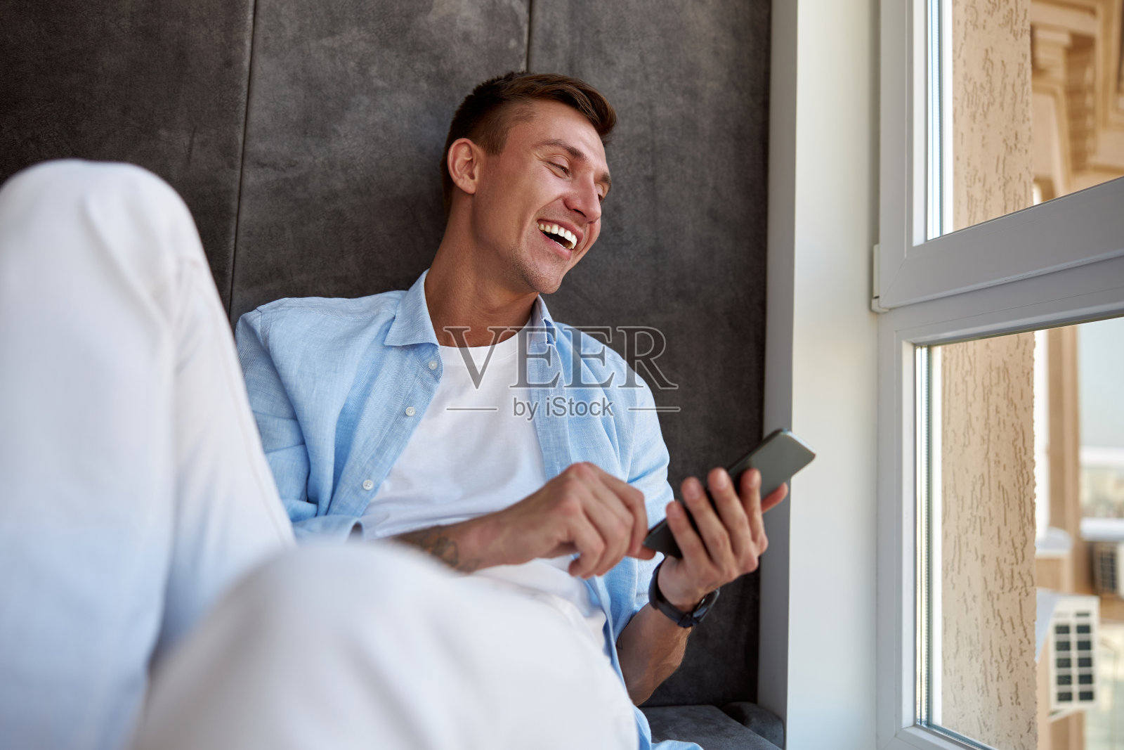 快乐的成年白人男性坐在全景窗旁,寒心照片摄影图片