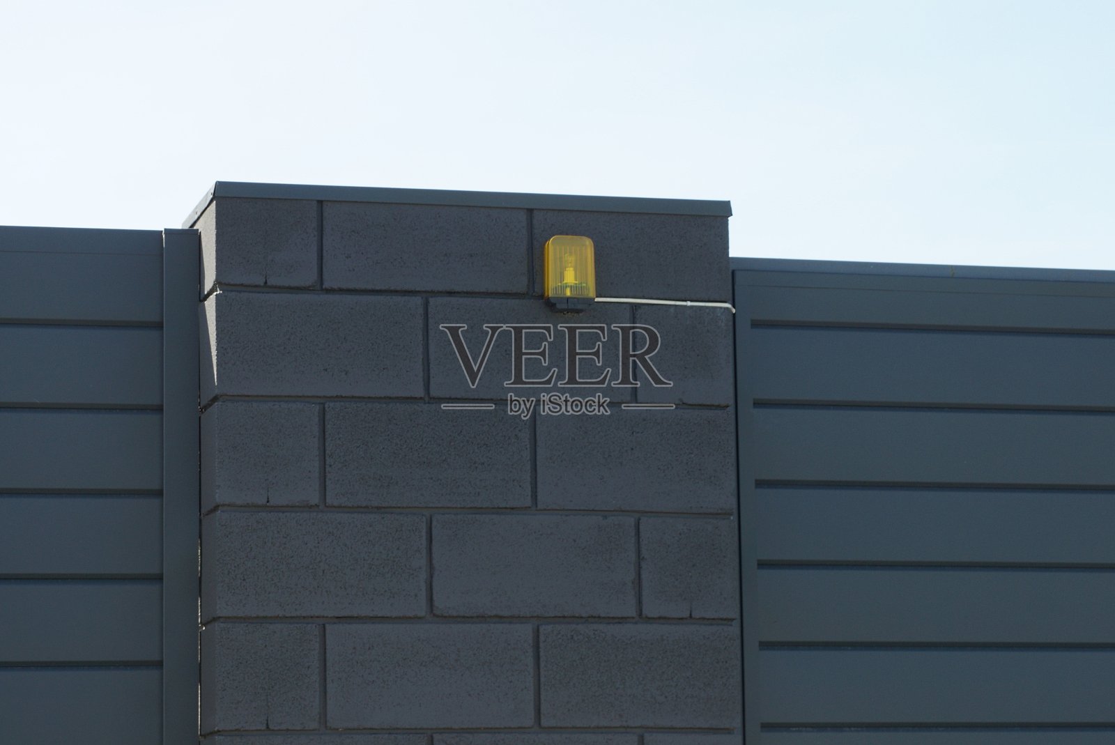 一盏黄色的信号灯挂在黑色的砖墙上照片摄影图片