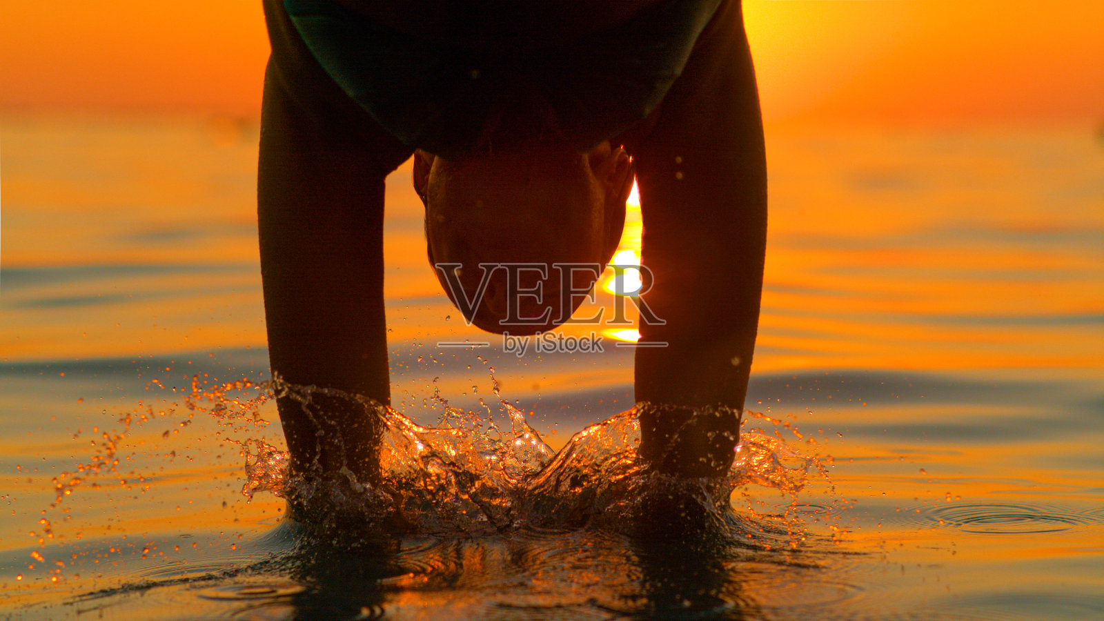 剪影:女游客一头扎进清新的海水中。照片摄影图片