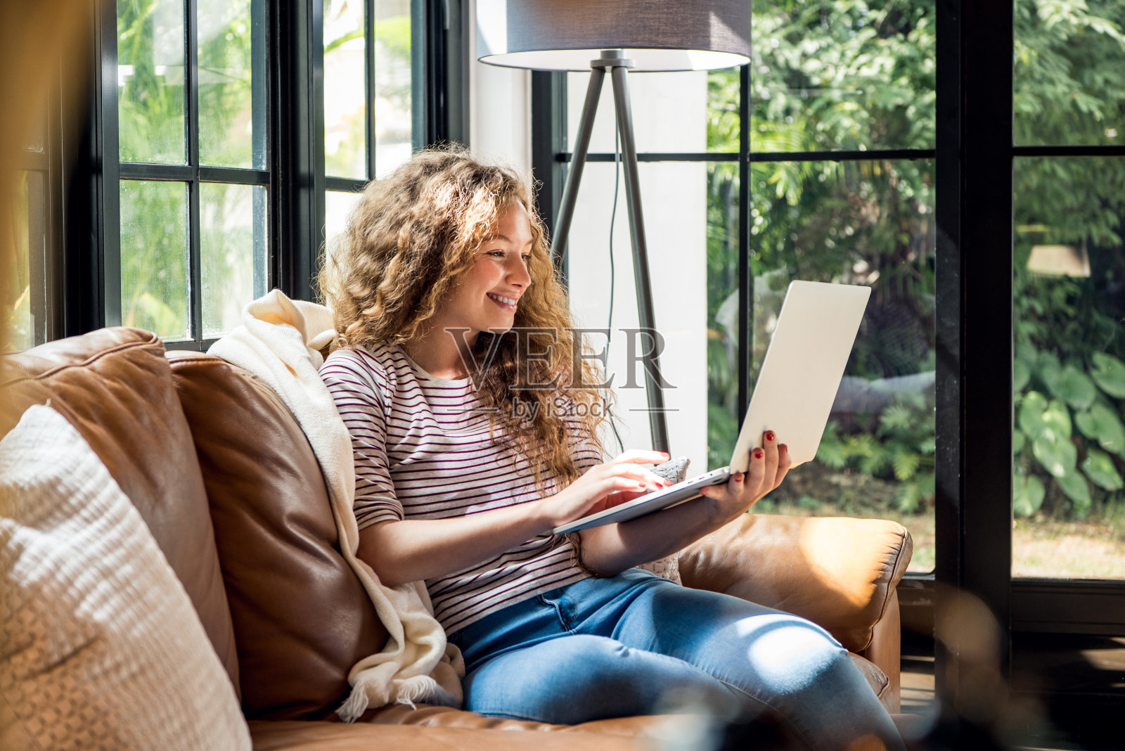 快乐微笑的白人妇女上网上网在客厅的沙发在家里的时间照片摄影图片
