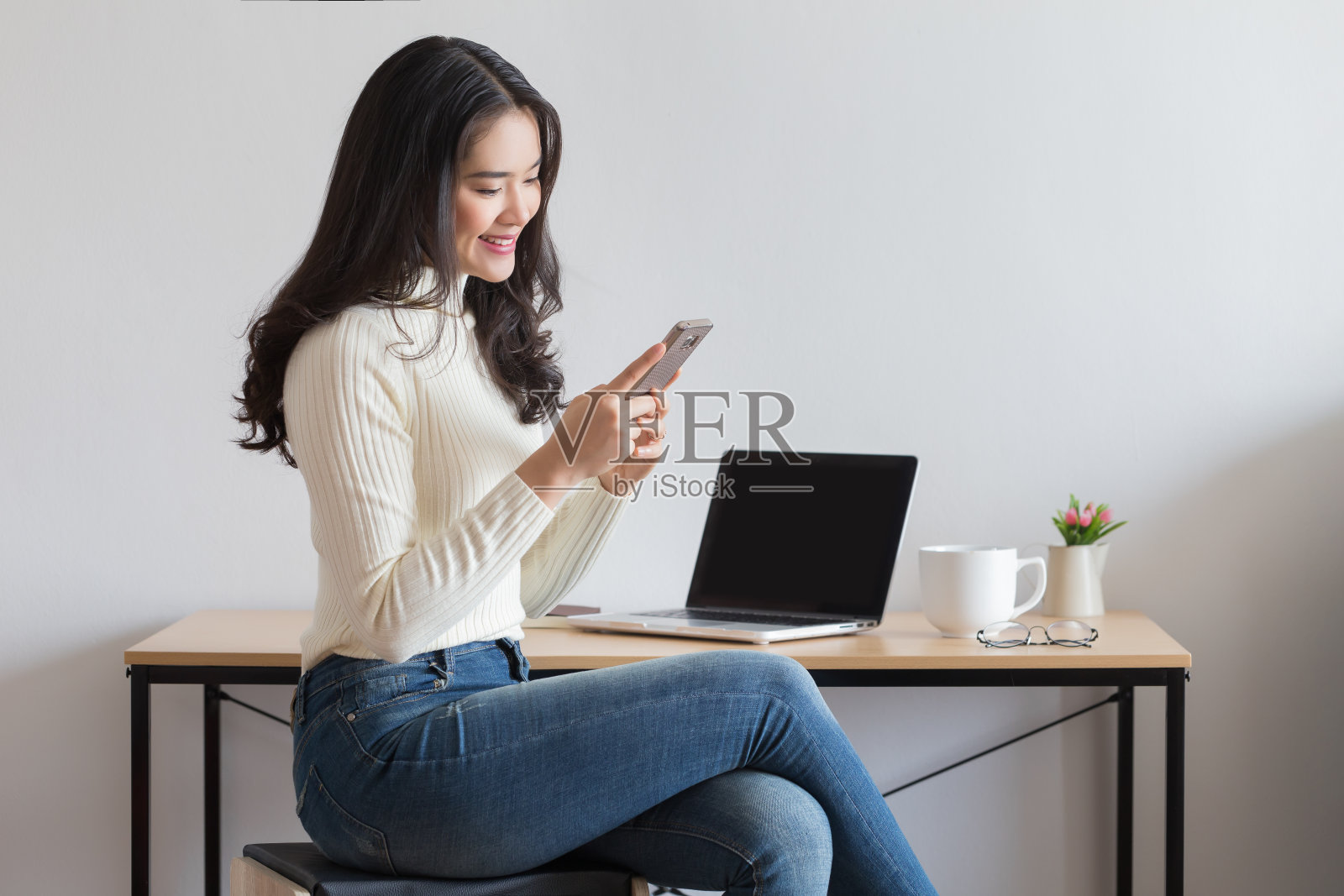 年轻快乐的亚洲女人在用智能手机。照片摄影图片