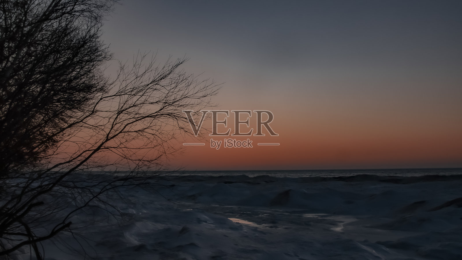 被厚厚的冰层覆盖的冰冻湖面上的日落照片摄影图片