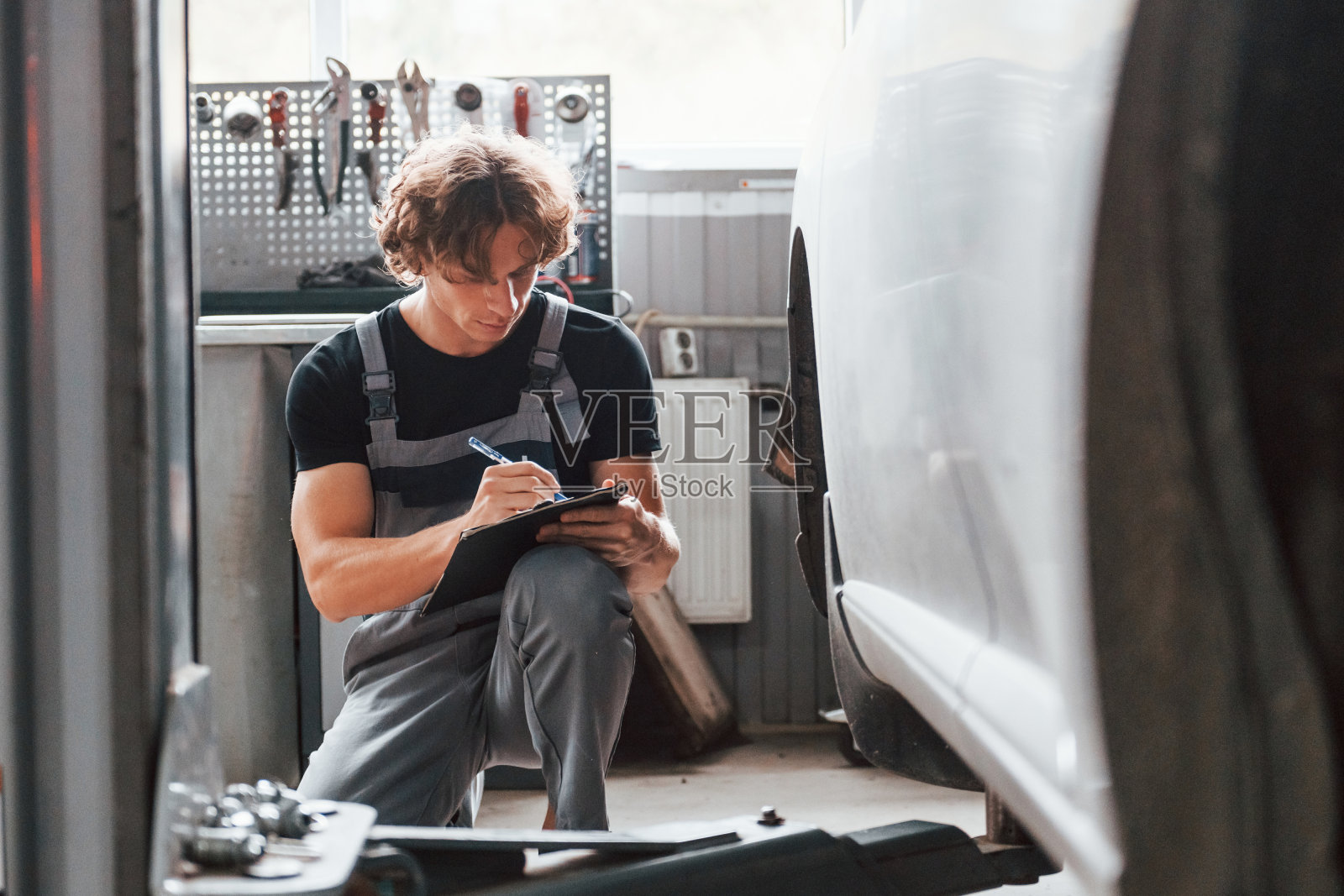 写在记事本。一个穿着灰色制服的成年男子在汽车沙龙工作照片摄影图片