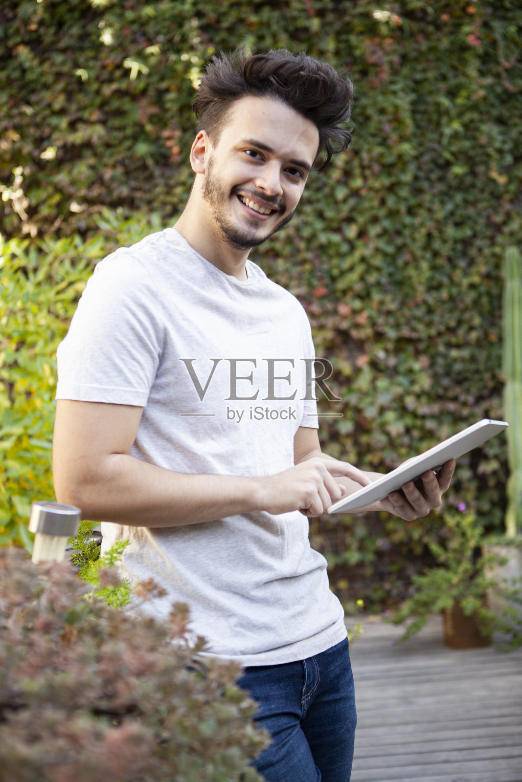 一名微笑的年轻人手持电子平板电脑站在城市花园照片摄影图片