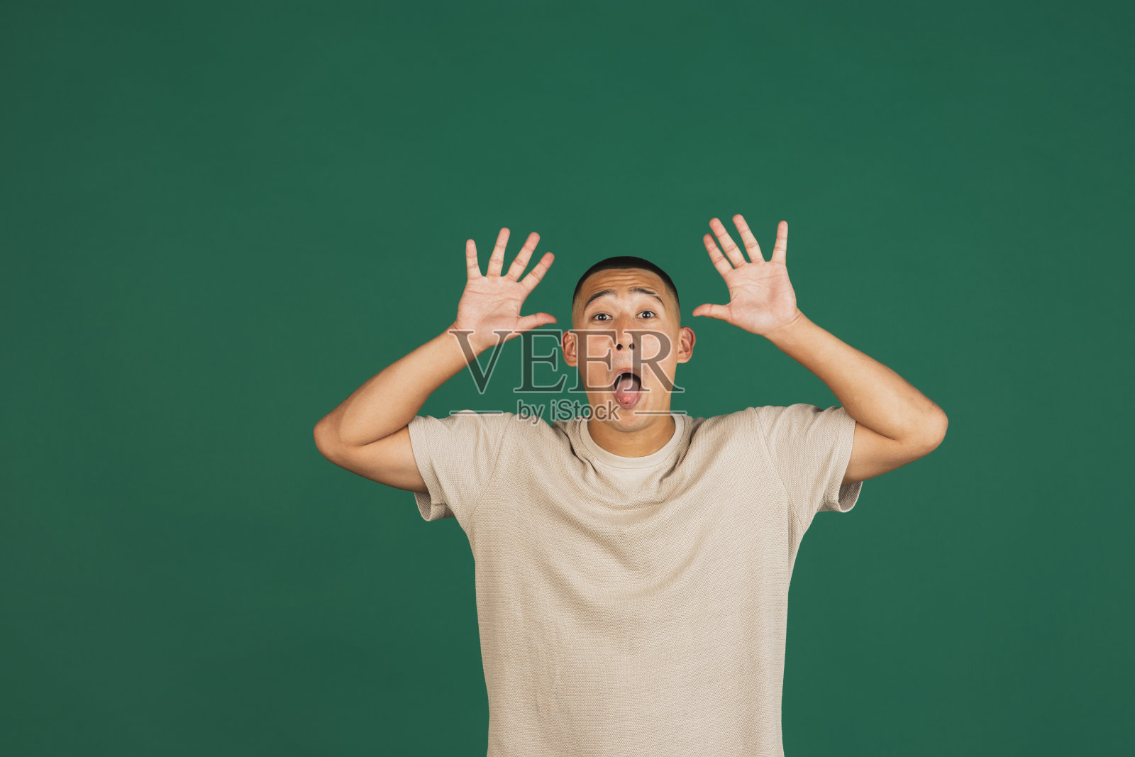 年轻英俊的亚洲人的肖像做的脸,有乐趣孤立在深绿色的工作室背景。照片摄影图片