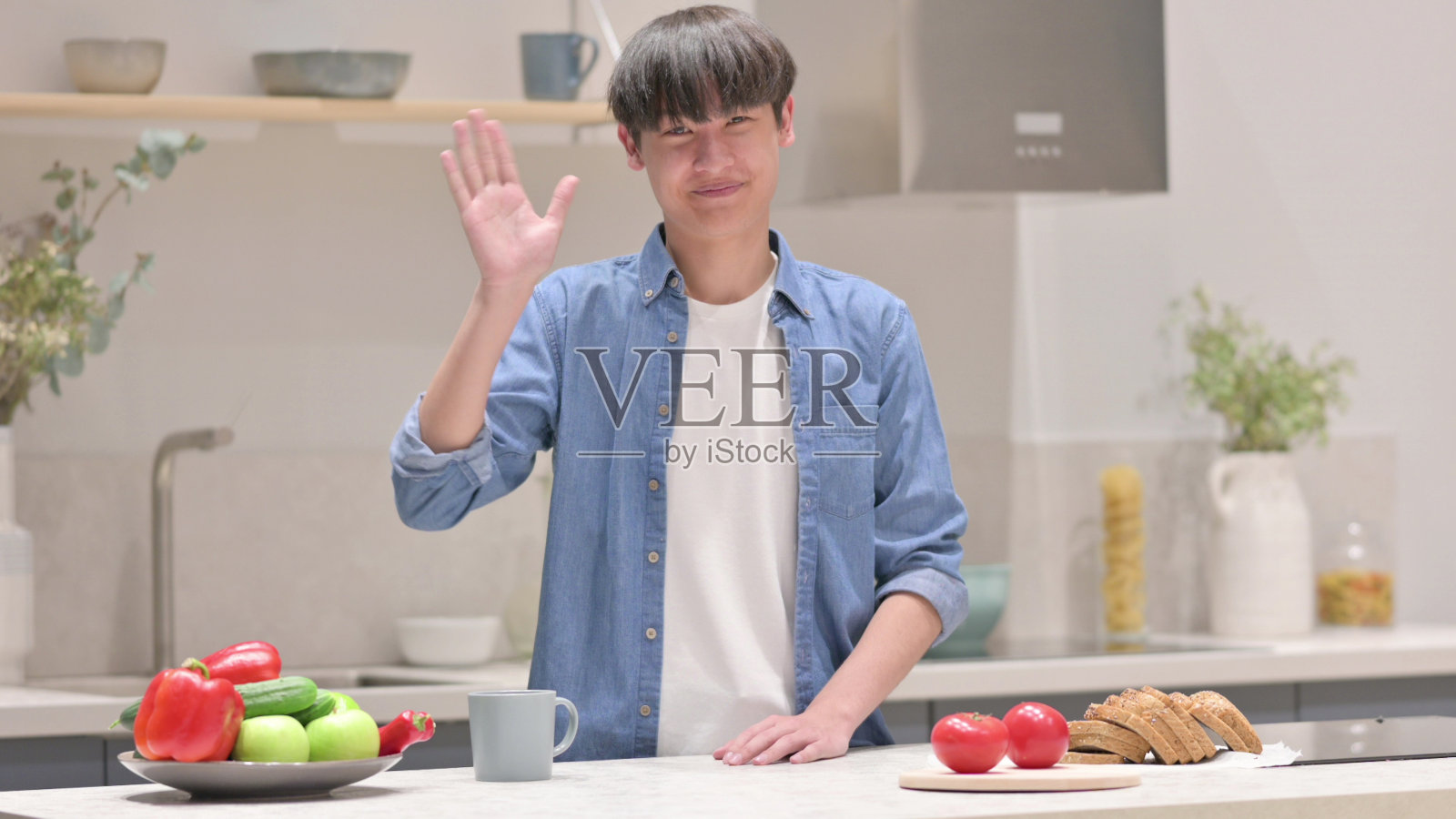 年轻的亚洲男子站在厨房里视频通话照片摄影图片