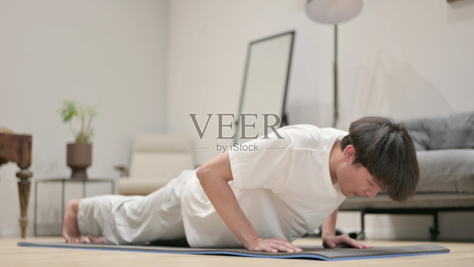 年轻的亚洲男人在瑜伽垫上做俯卧撑照片摄影图片